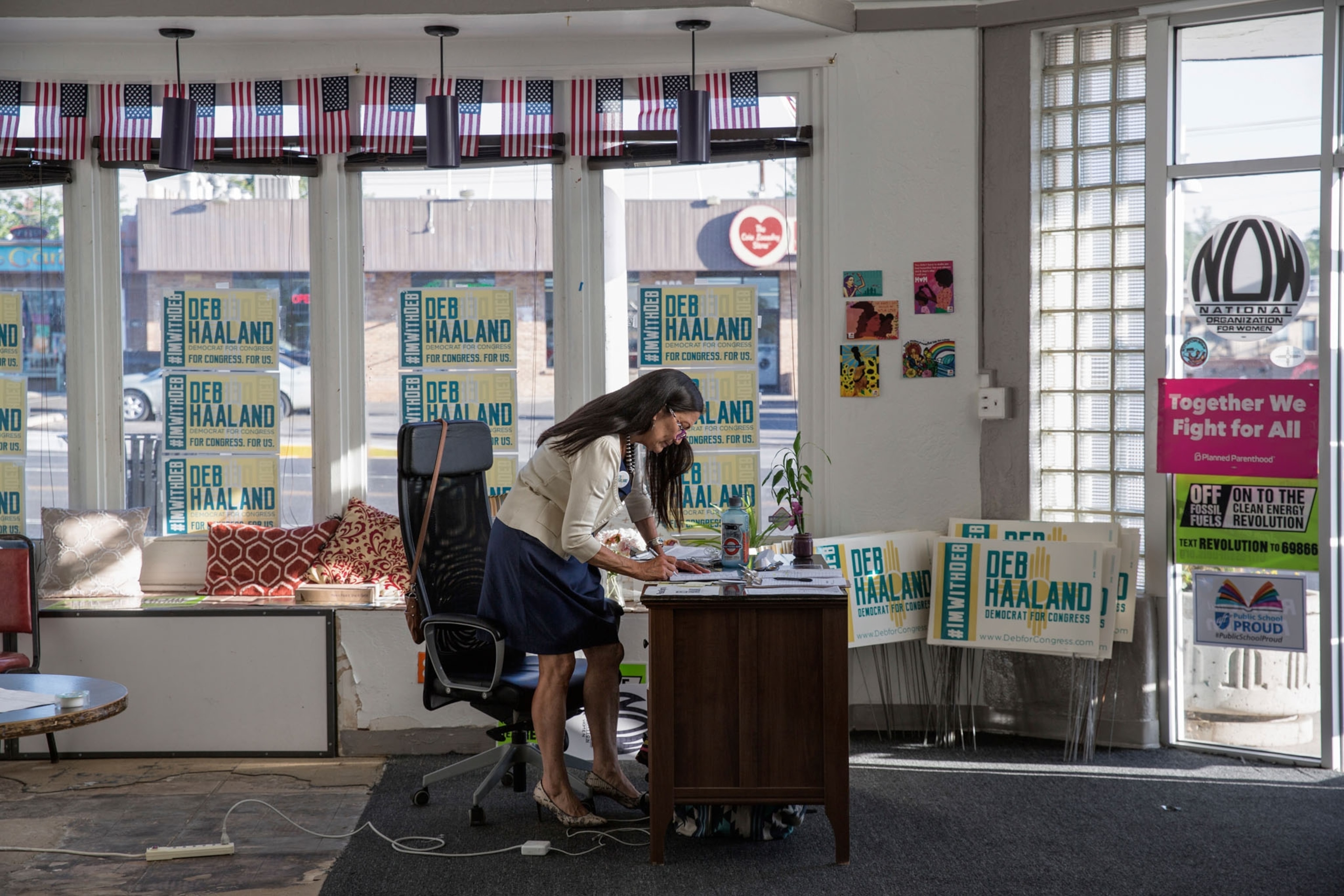 a woman standing in an office surrounded by political signs