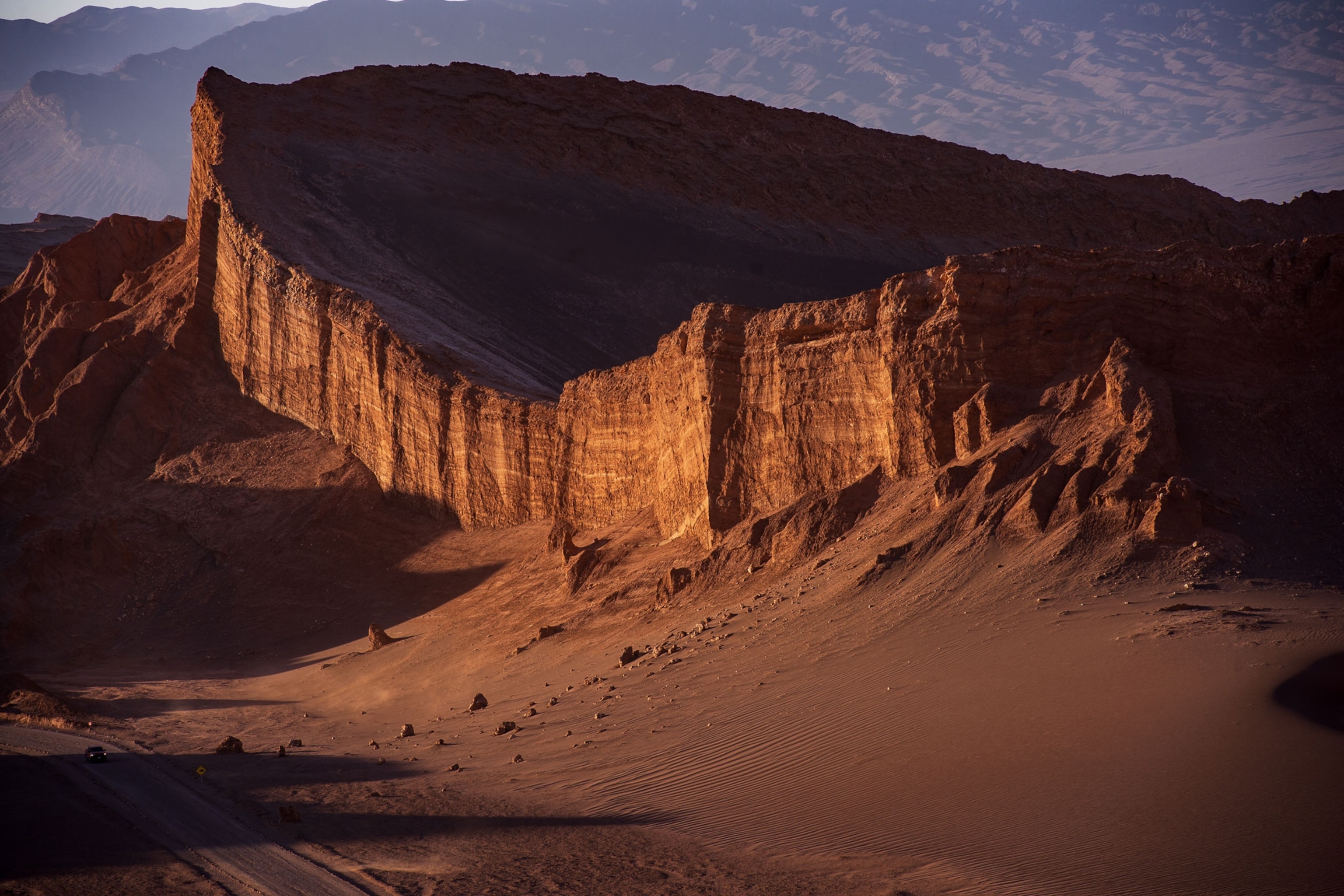 sun sets on the edge of a rock wall in the desert