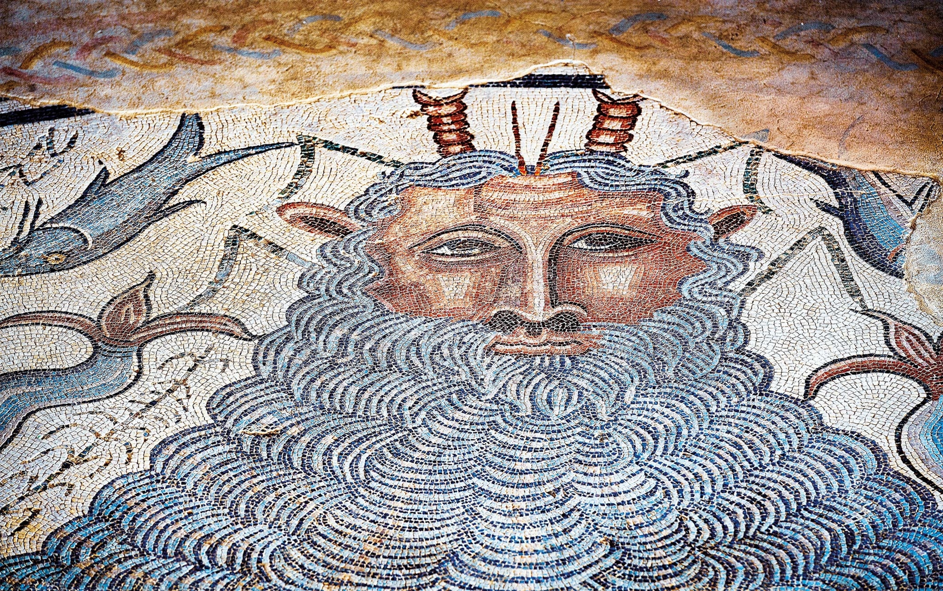 A mosaic on the wall shows a main with a long flowing white beard and horns