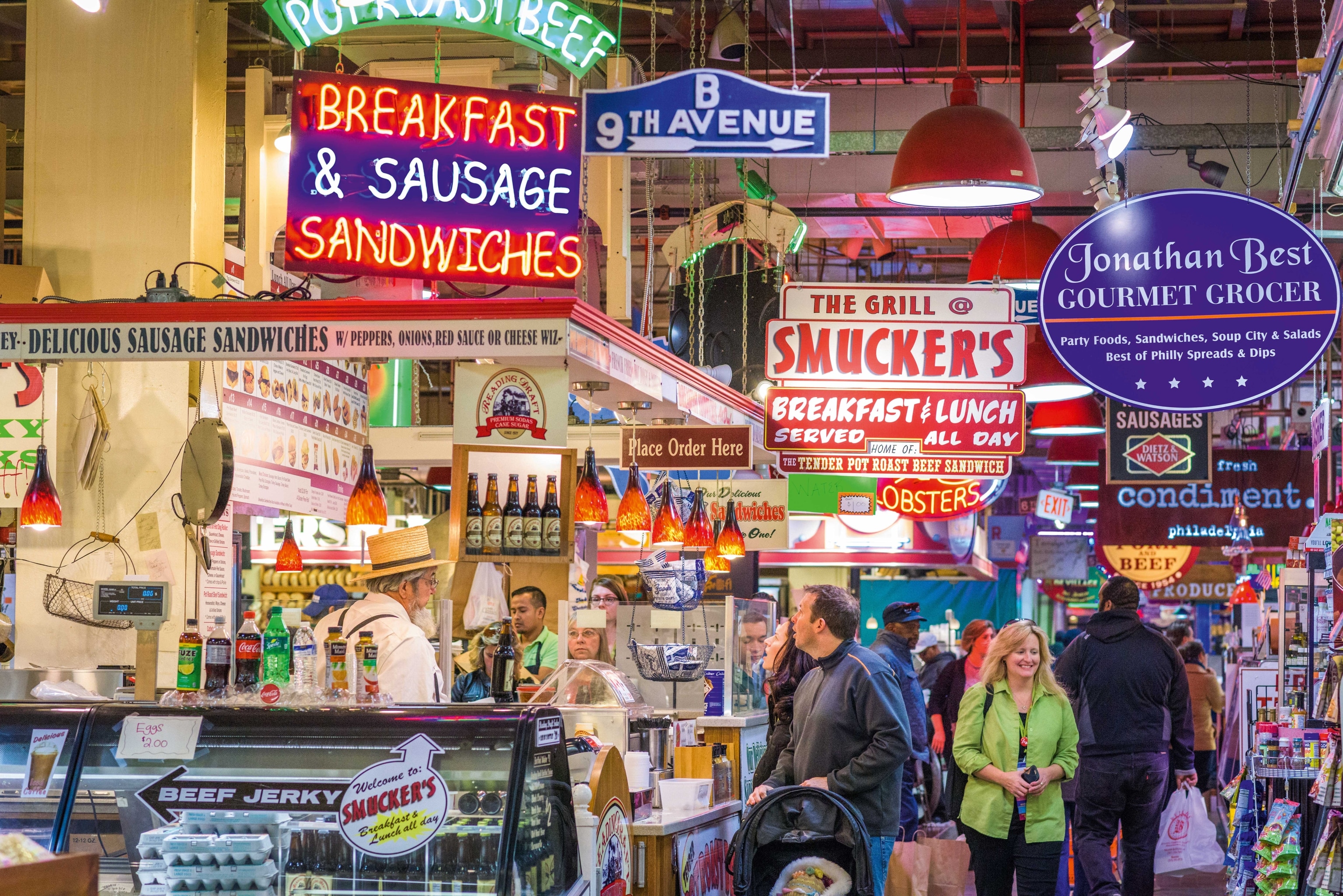 A busy market with colourful signs and plenty of food stalls.