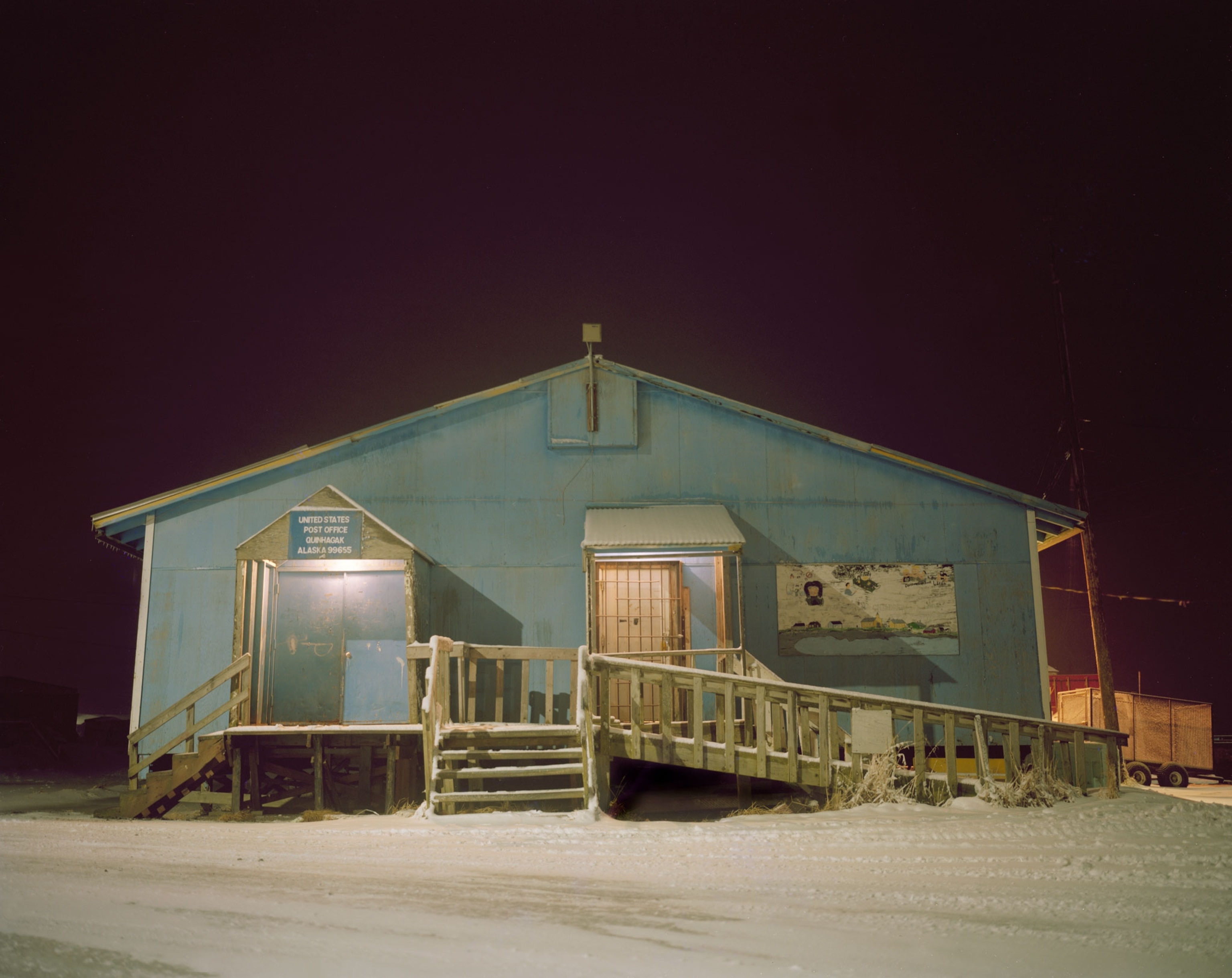 a blue building at night surrounded by snow