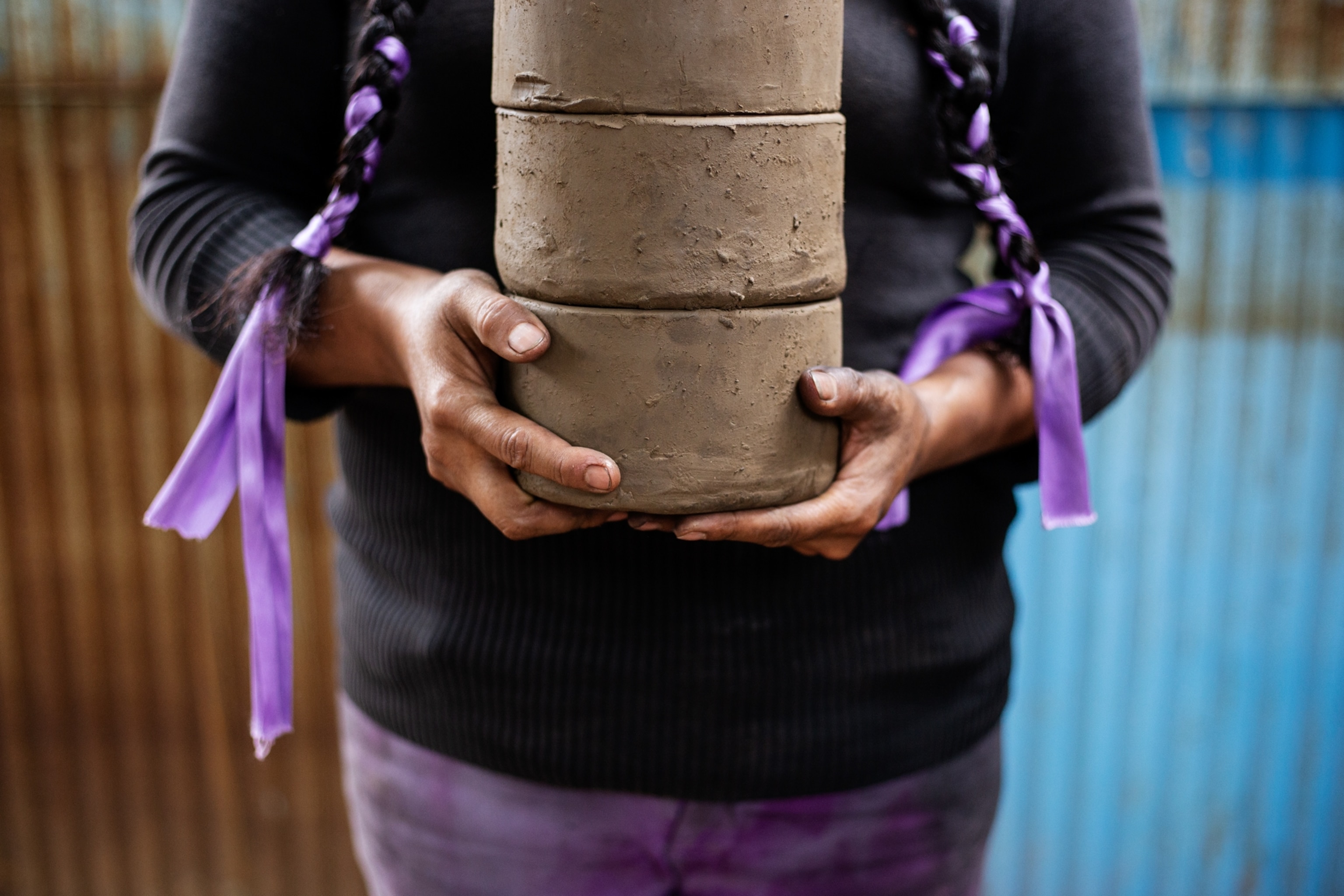 Portrait of Graciela Simon holding pieces of pottery in her creation proces