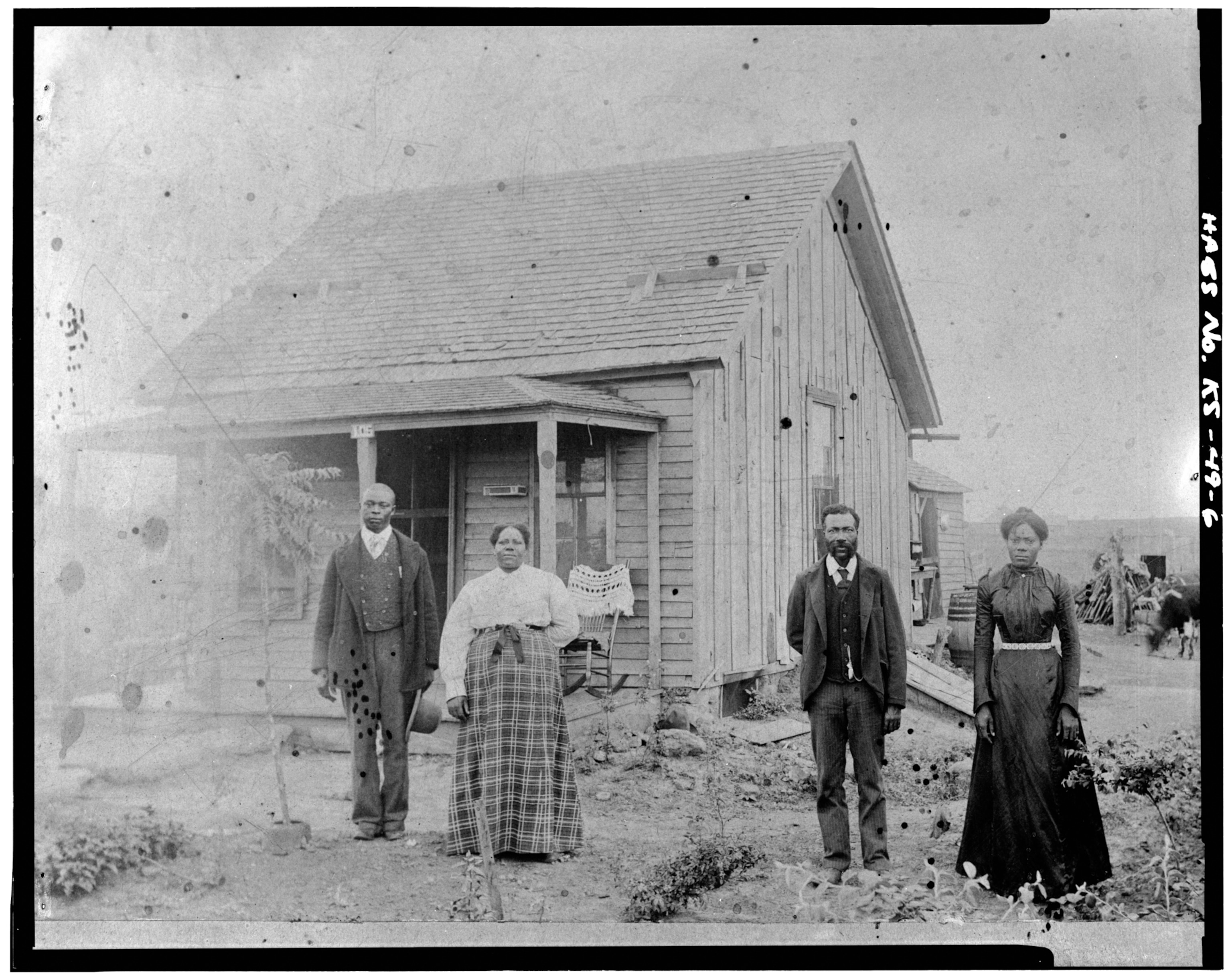 Black and white image of family, in front of oxen.