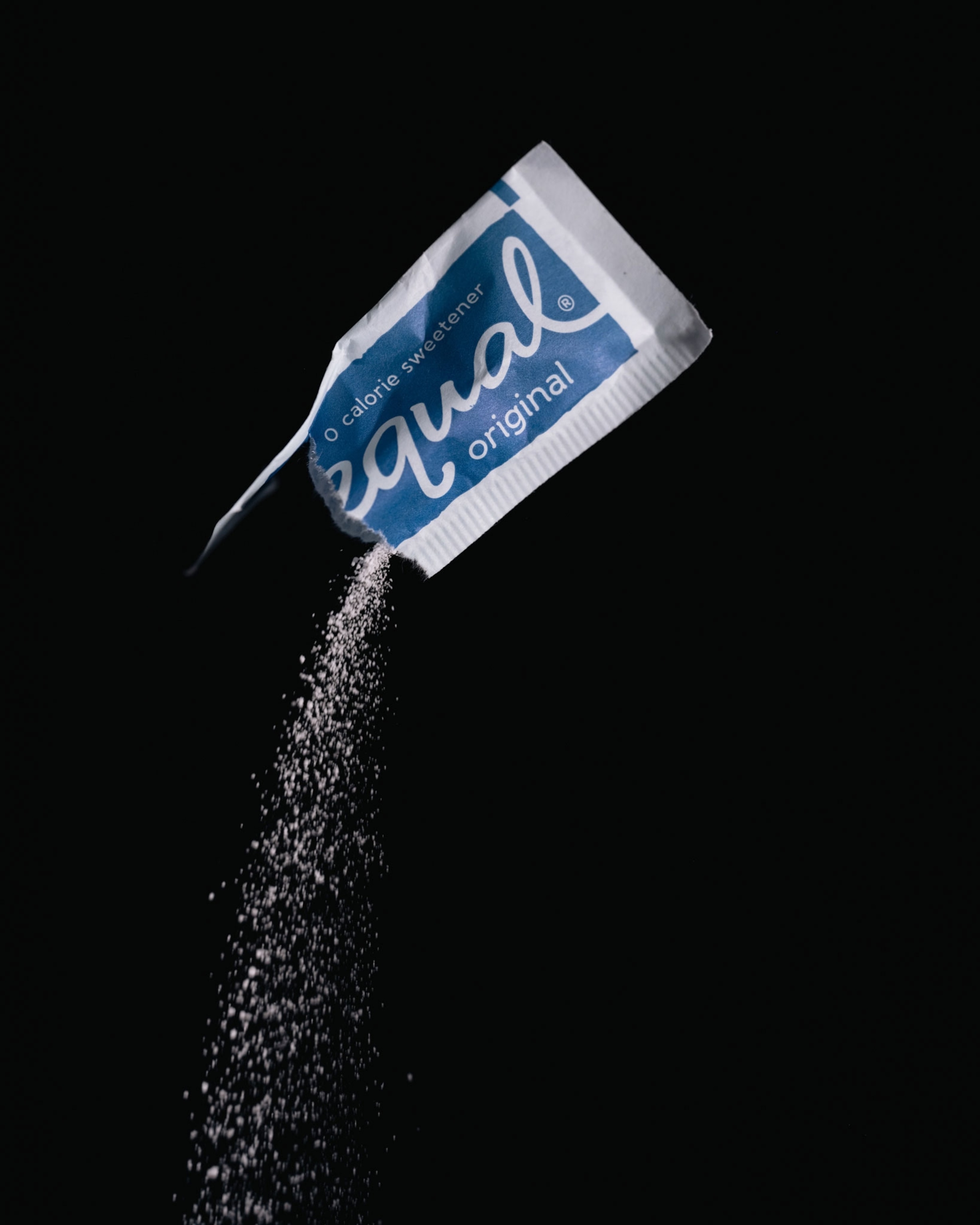Studio shoot with black backdrop showing packets of artificial sweeteners