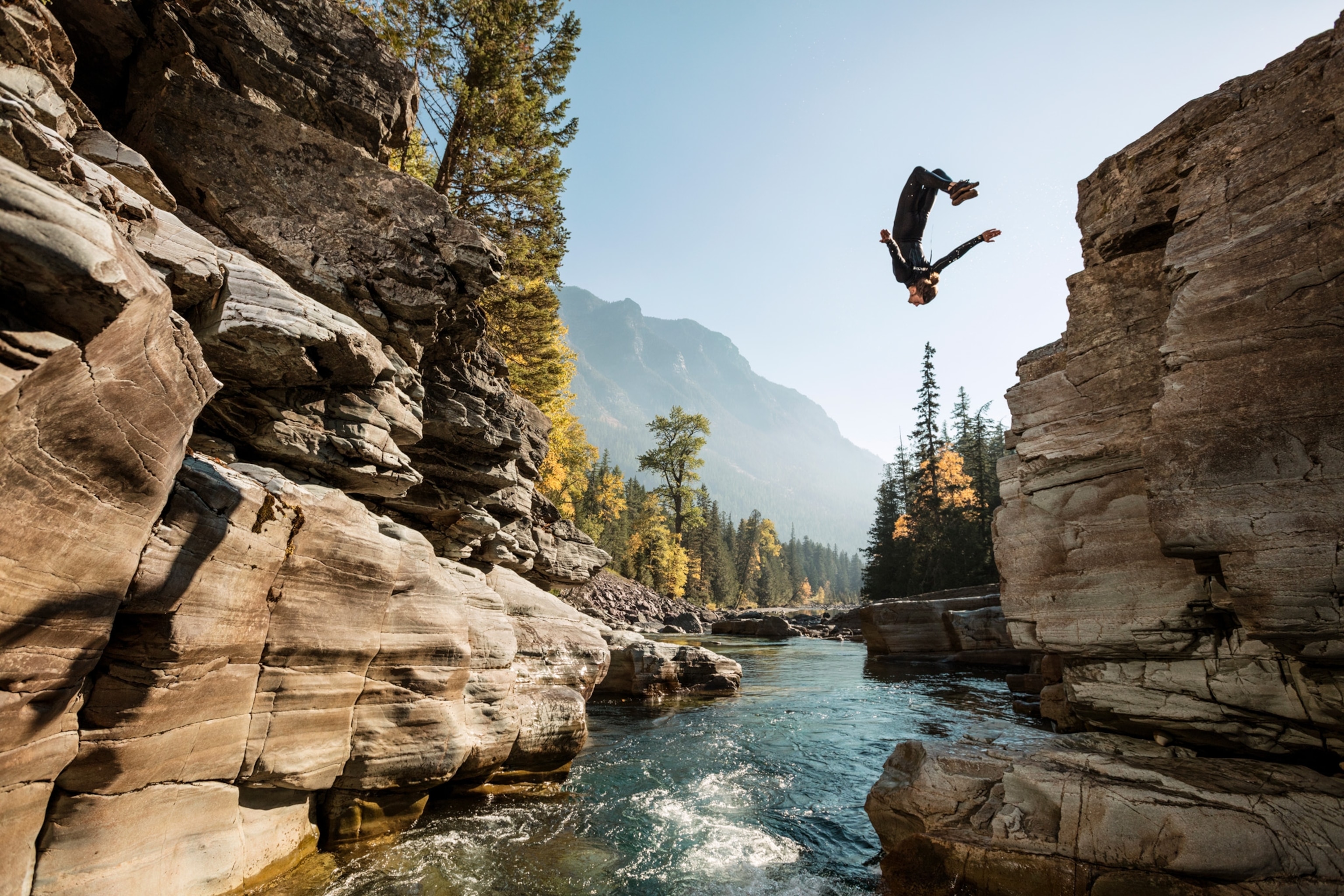 Photo of man diving into creek from mountain