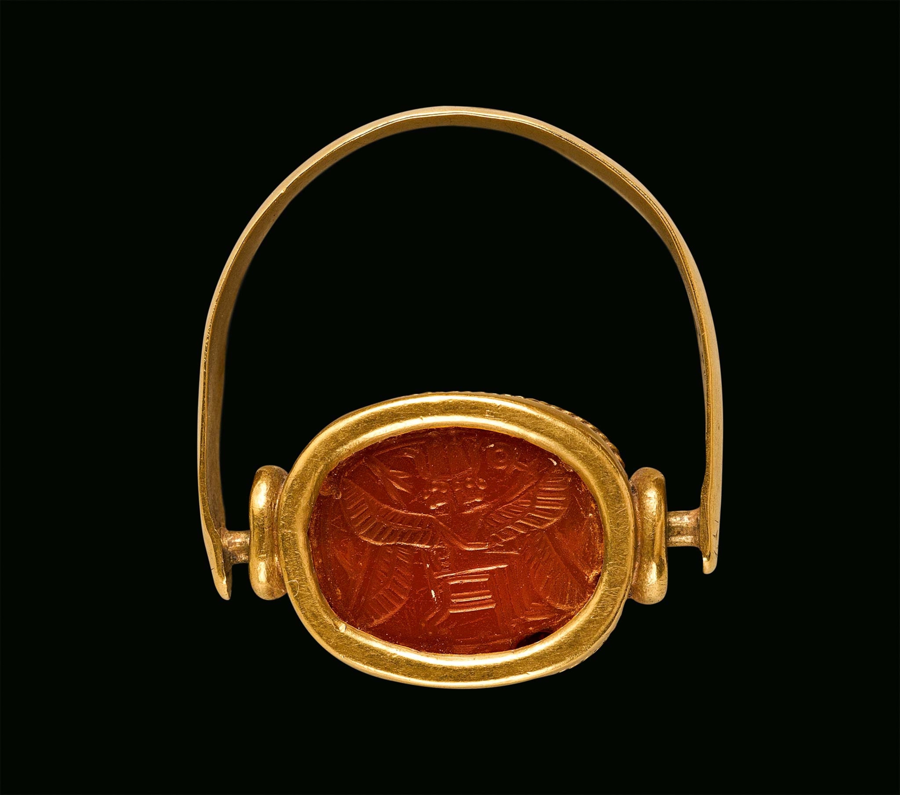 A gold swivel ring is decorated with the image of a two-headed, four-winged god wearing a double crown