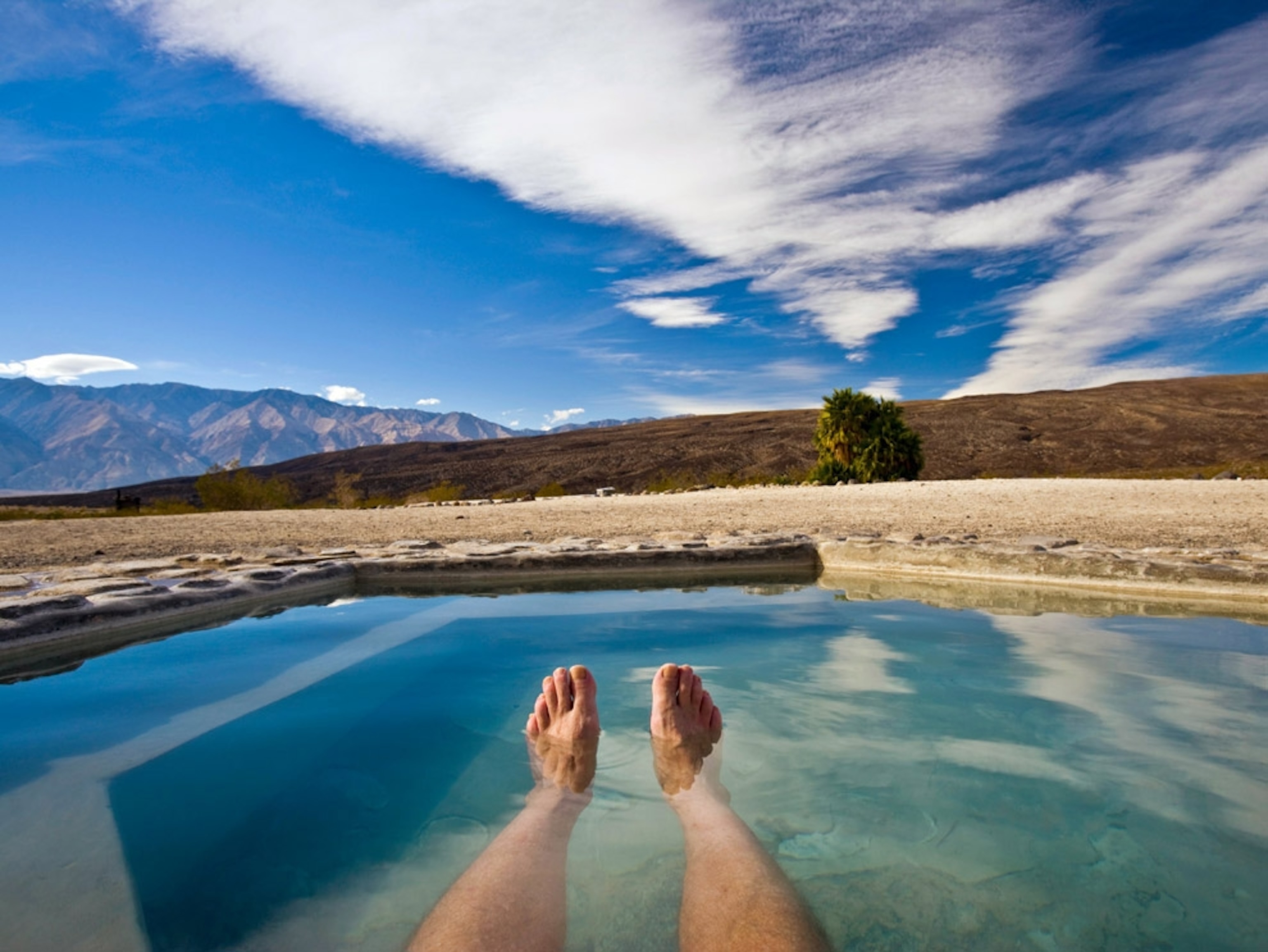 Person floating in the blue-green water of a spring