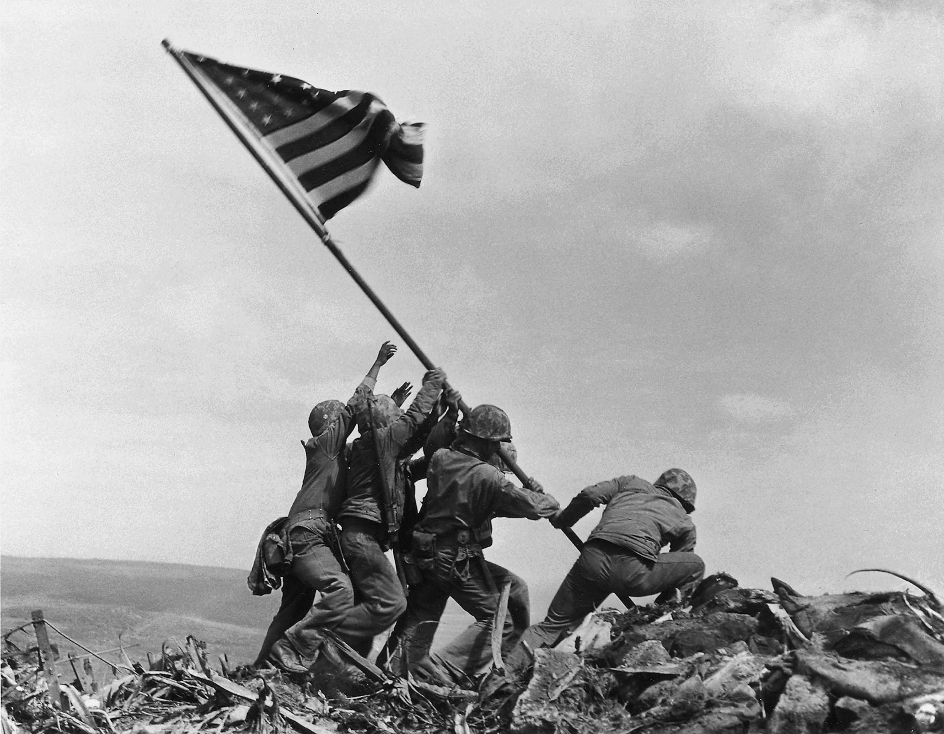 soldiers bolstering a american flag into a mountain top