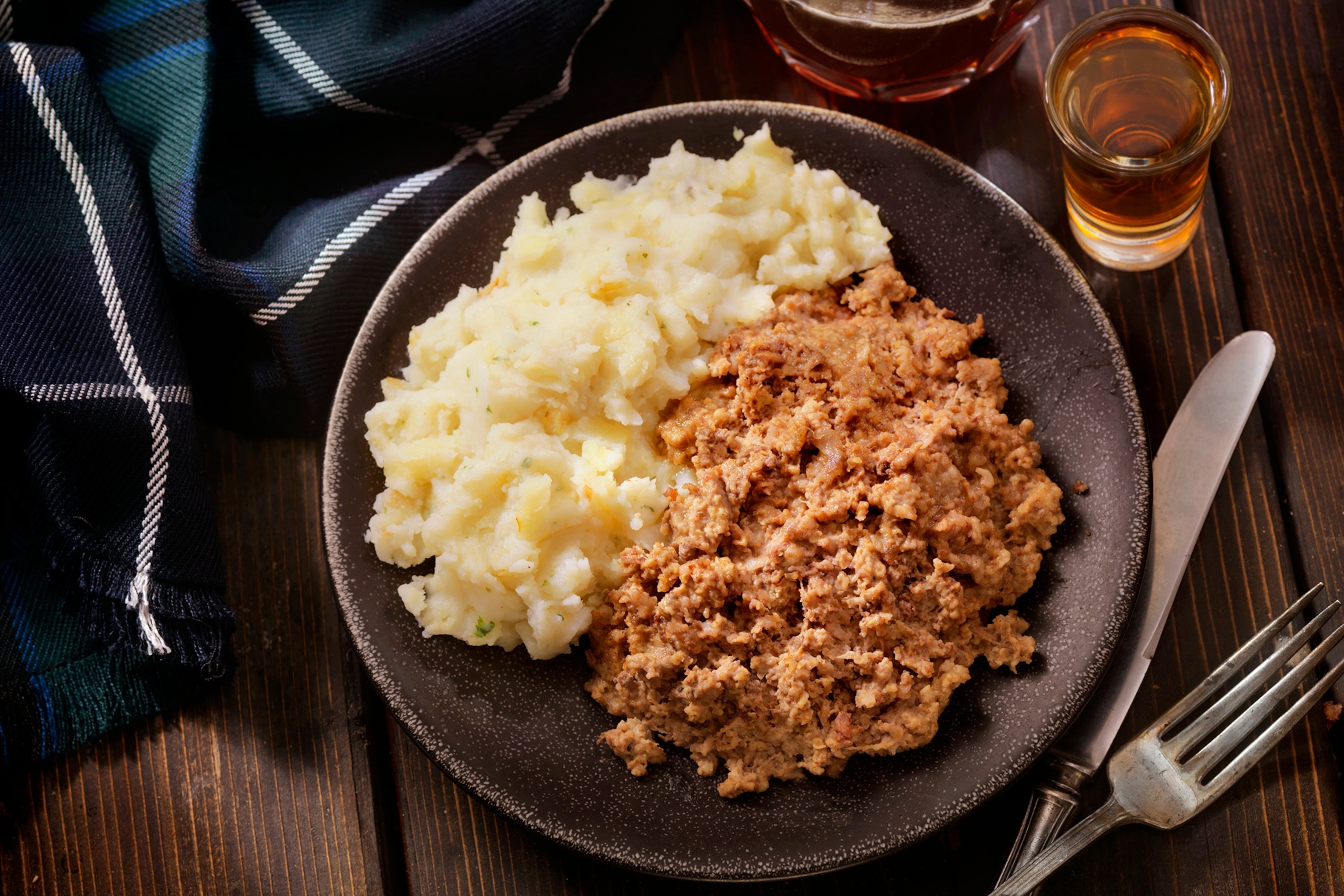 A plate of haggis with mash and a side of beer.