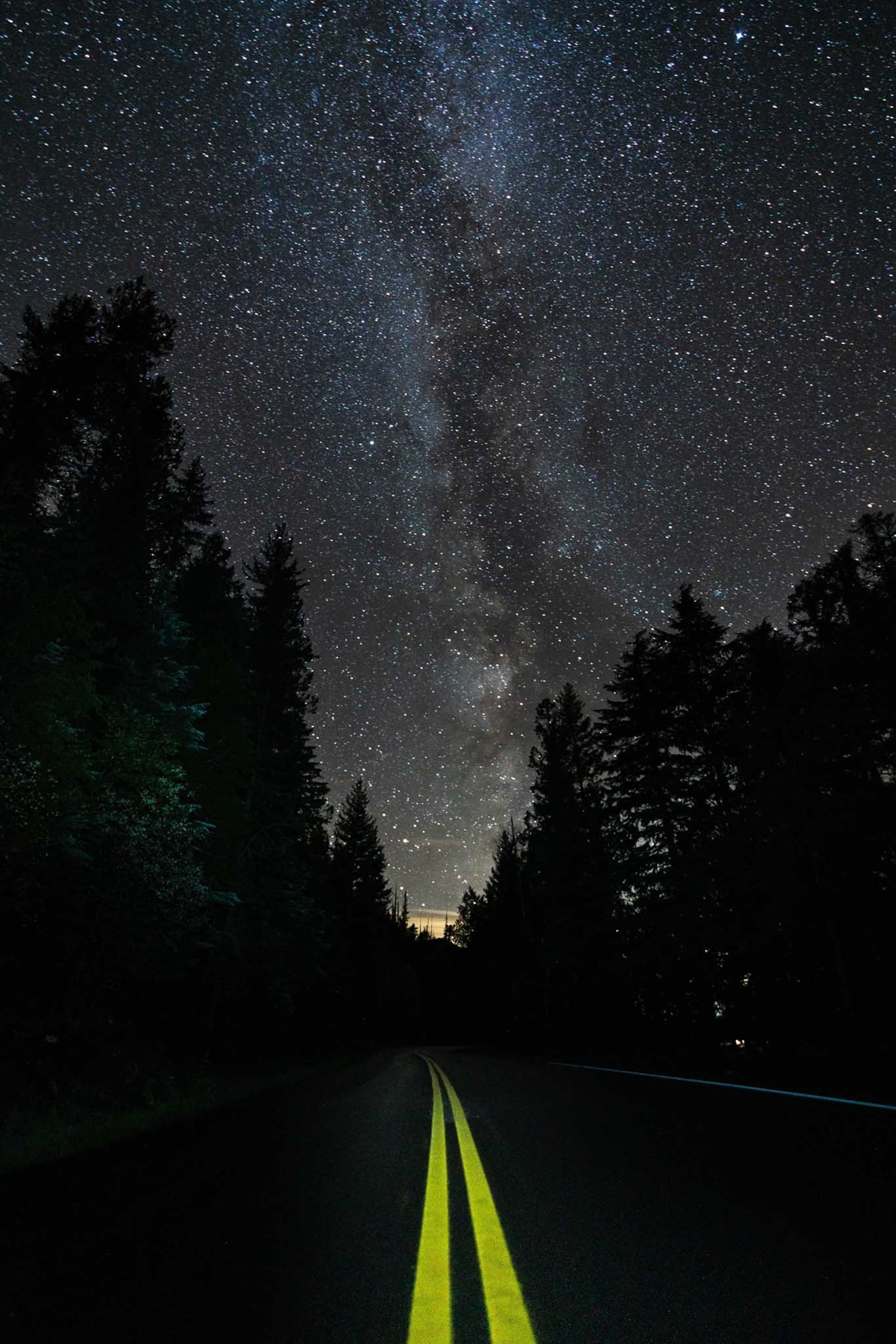 The milky way and starts lighting up on top of the road just beside Macdonald Lake, Montana.