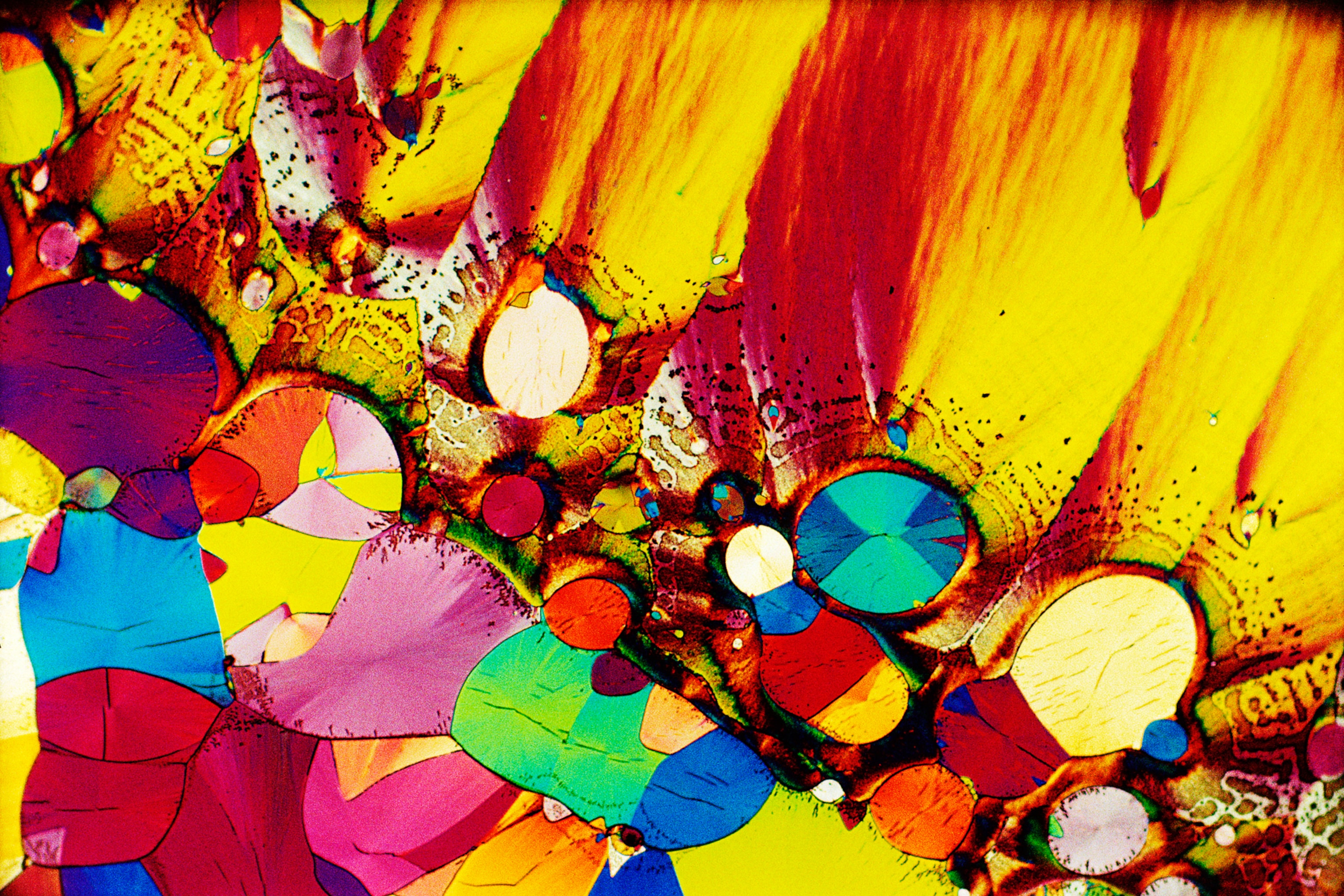 A rainbow of rounded colorful crystals amid a smearing of golden yellow and red.
