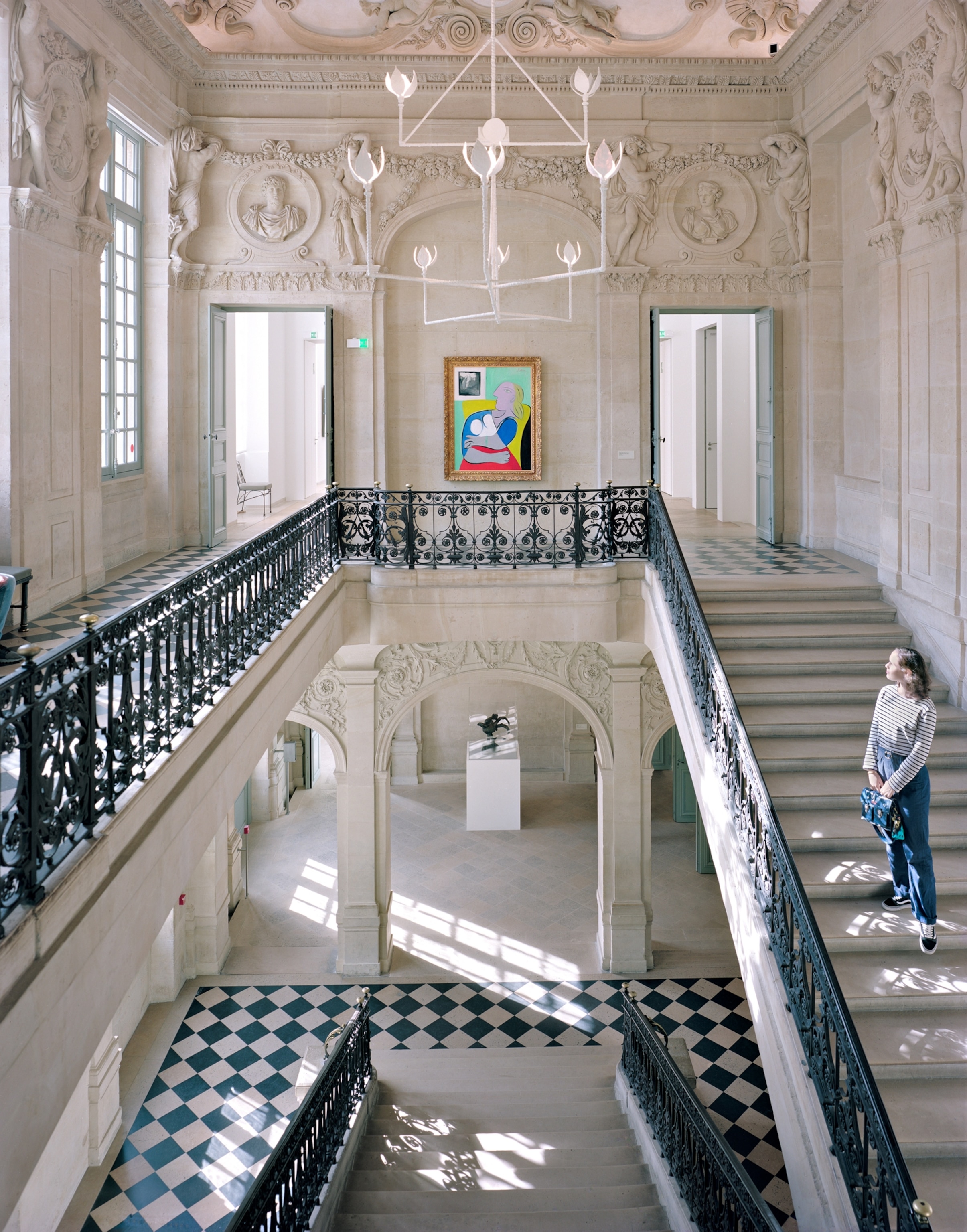 a young woman standing on staircase in a museum looking up at a Picasso painting