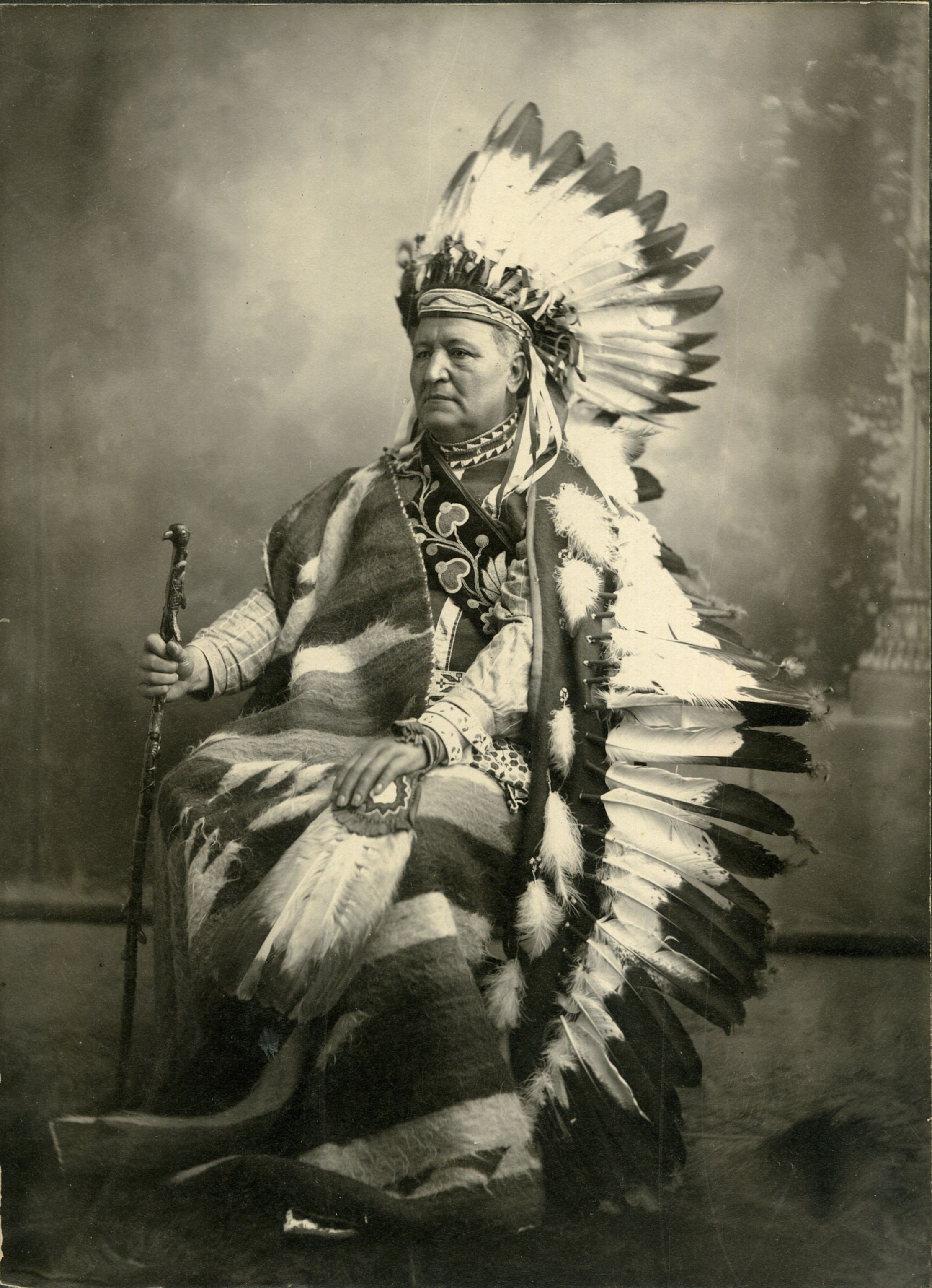 a seated man wearing Indigenous regalia