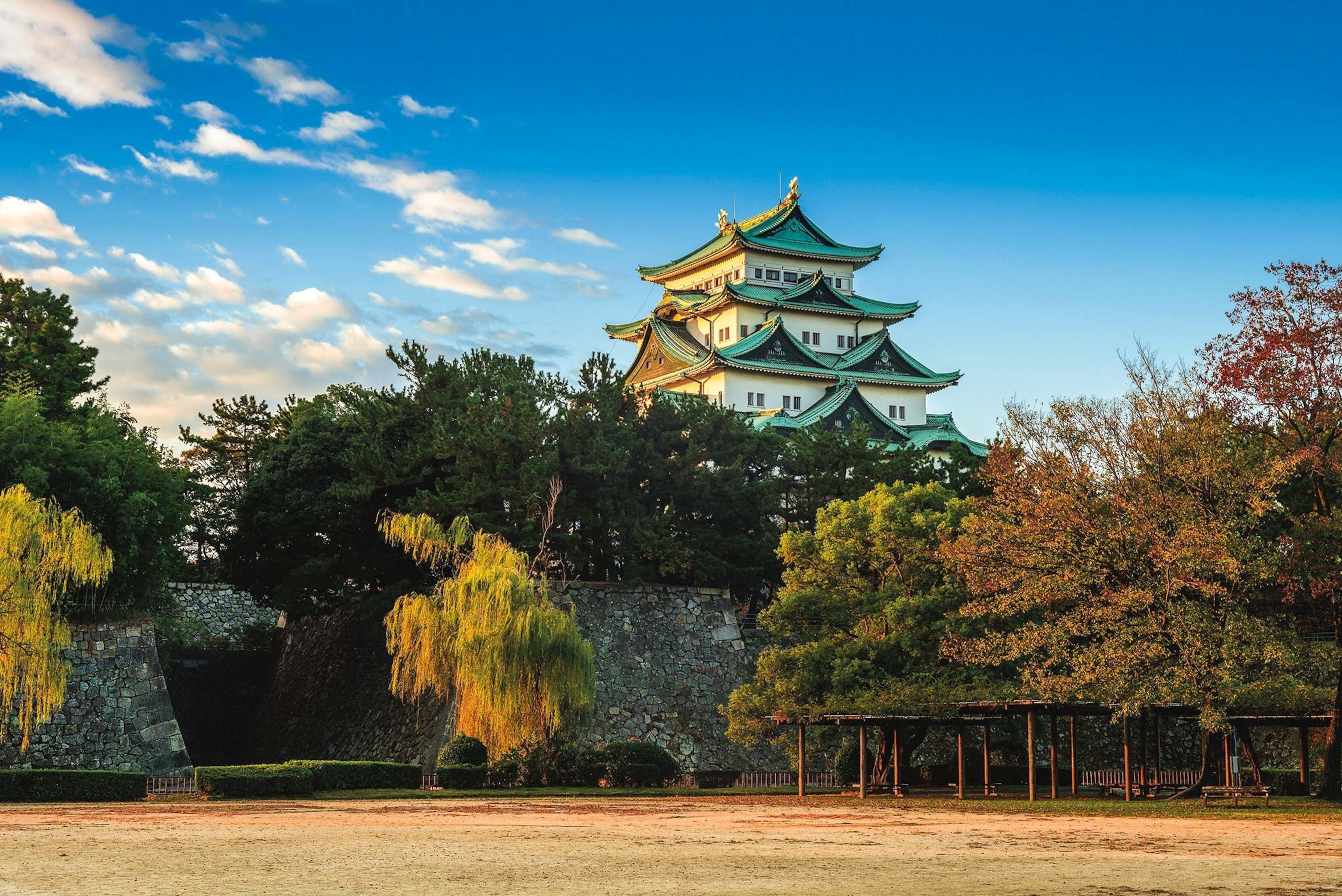 Nagoya Castle stands above trees with a field in front