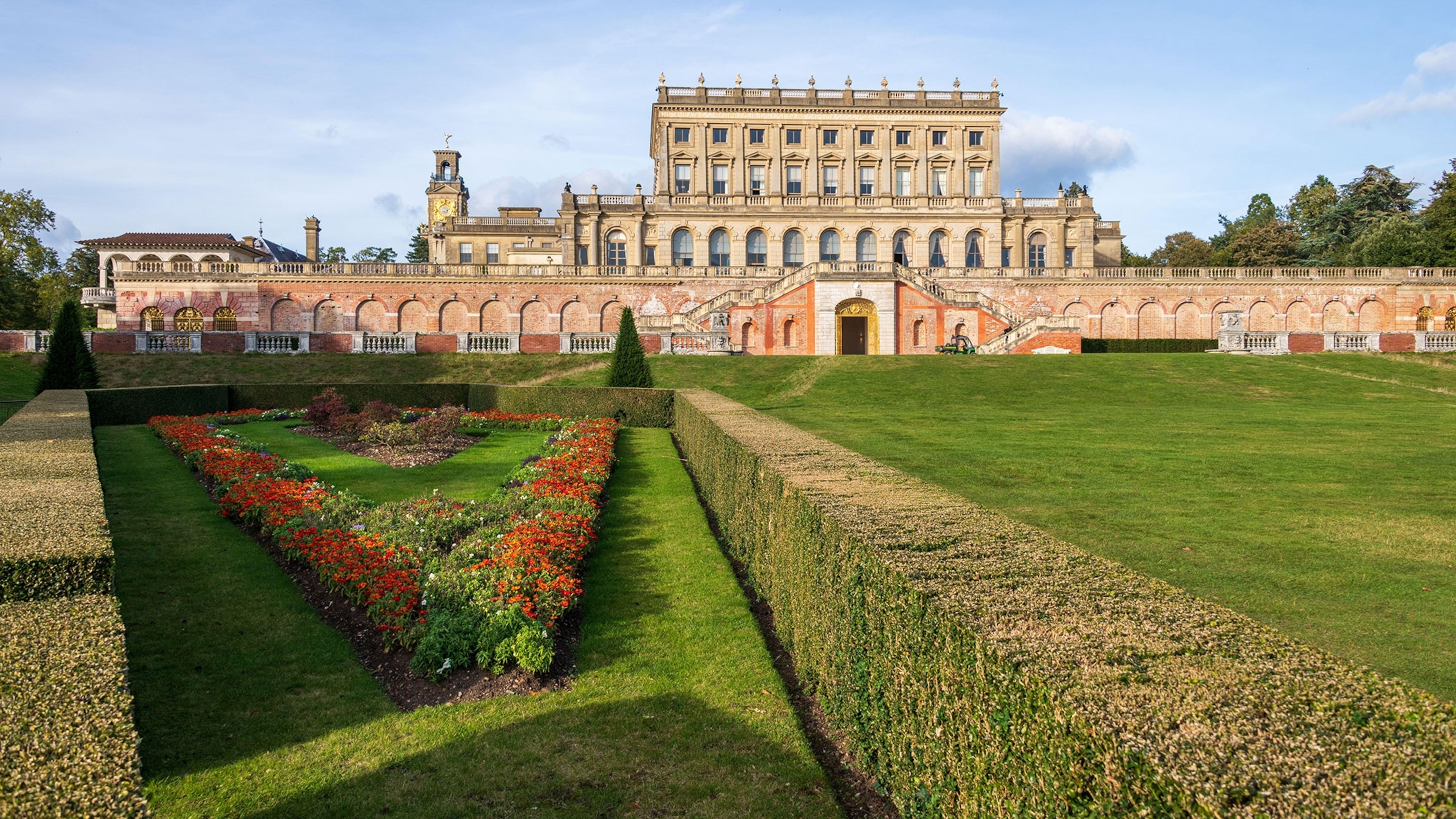 An english castle with a sprawling, green yard and rose bushes