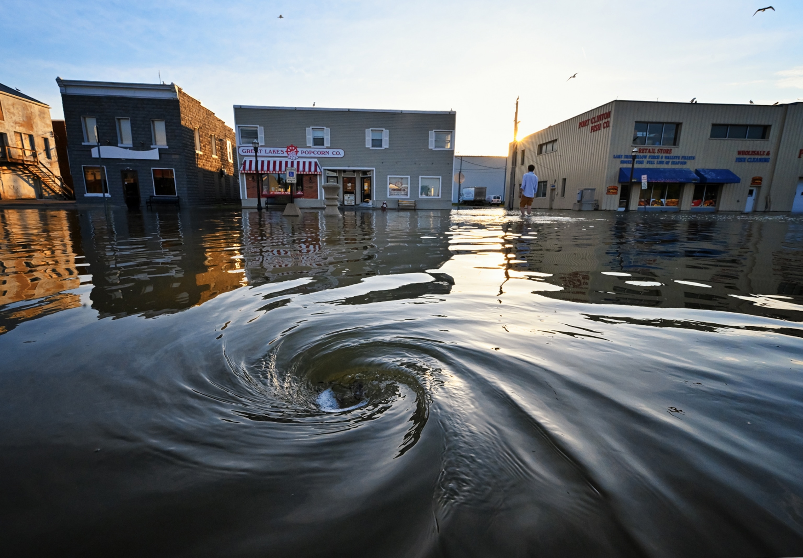 whirlpool in floodwater on town street.