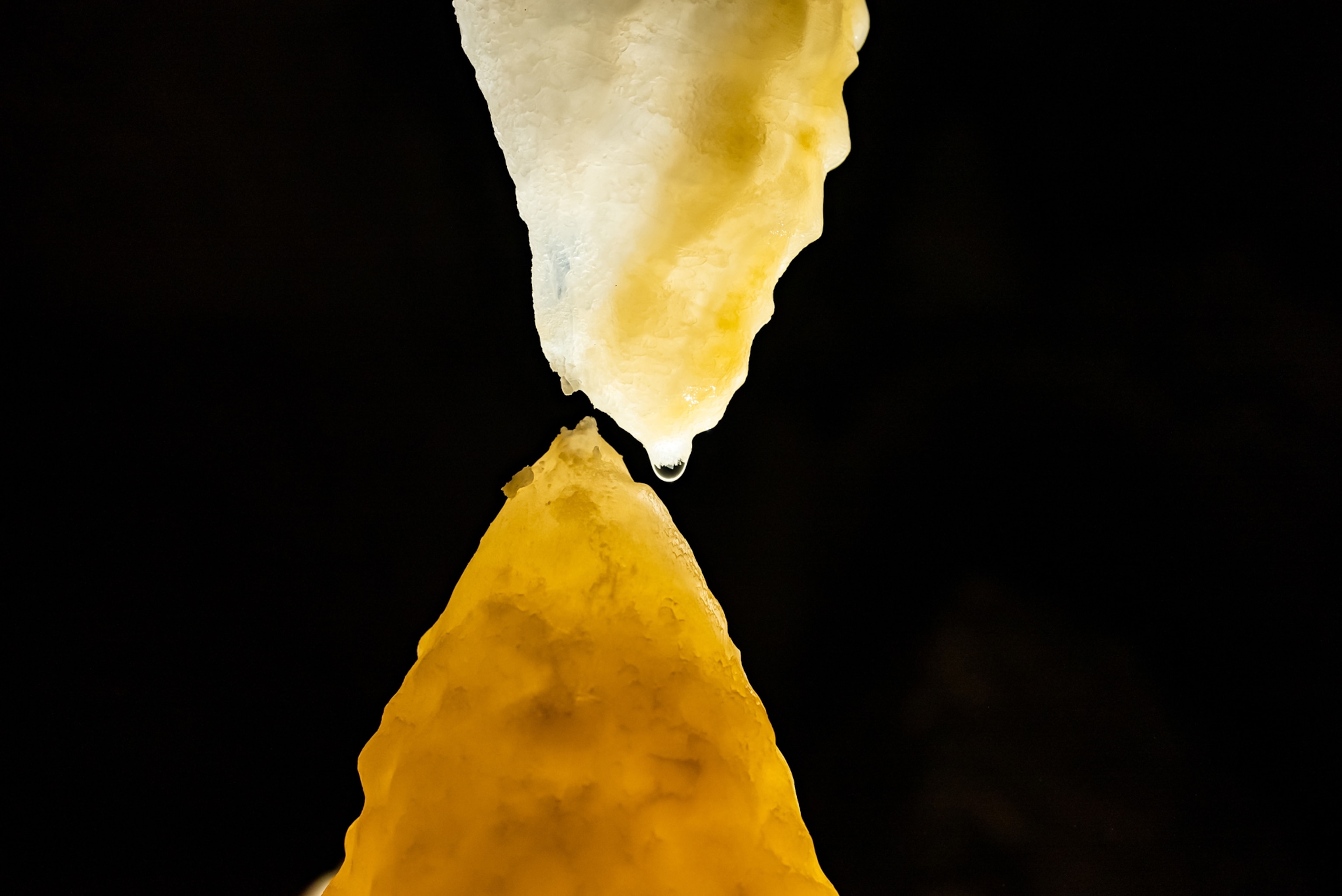 Picture of pointed stalactite and stalagmite touching.