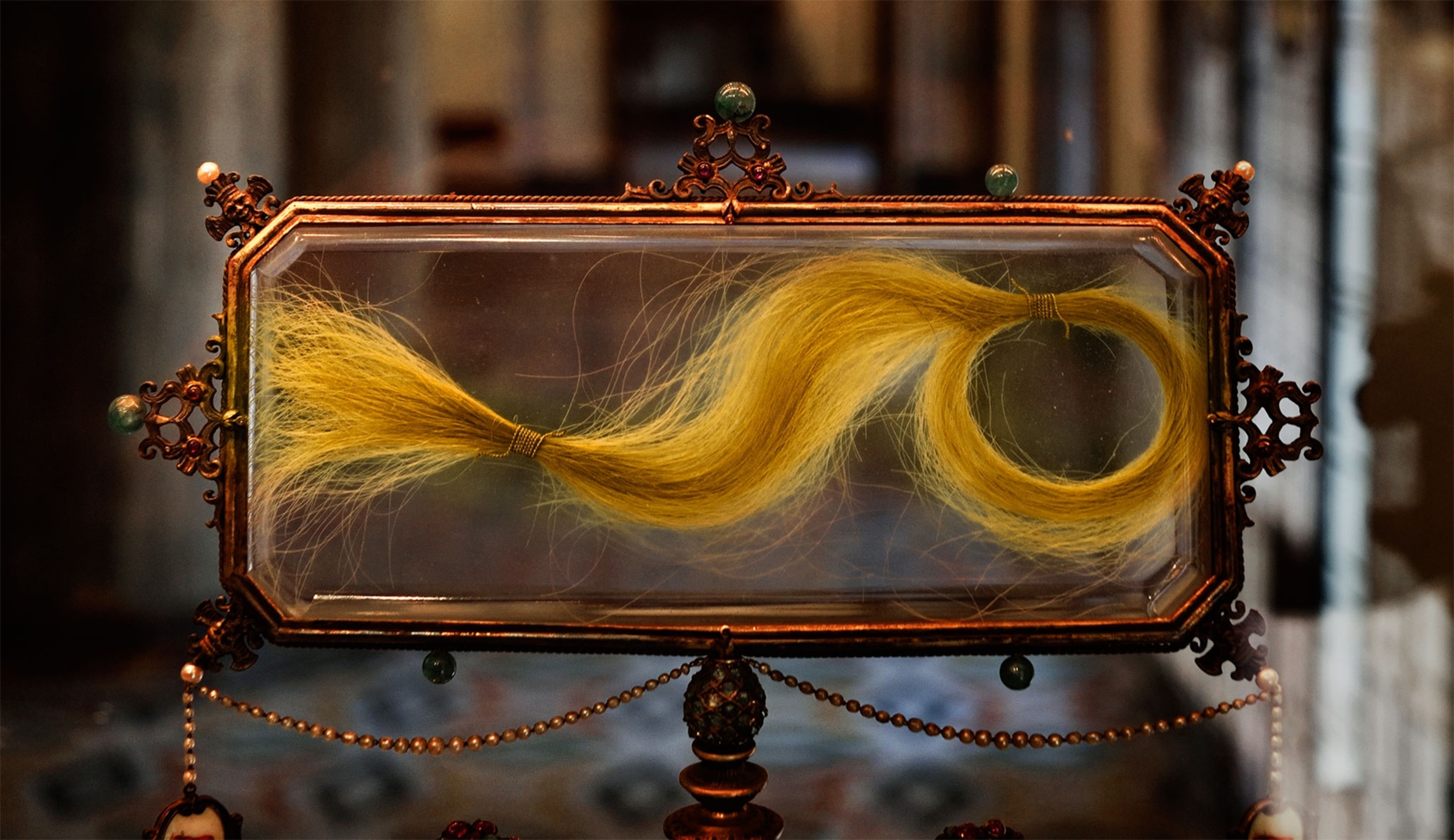 A lock of blonde hair locked in a decorated glass case