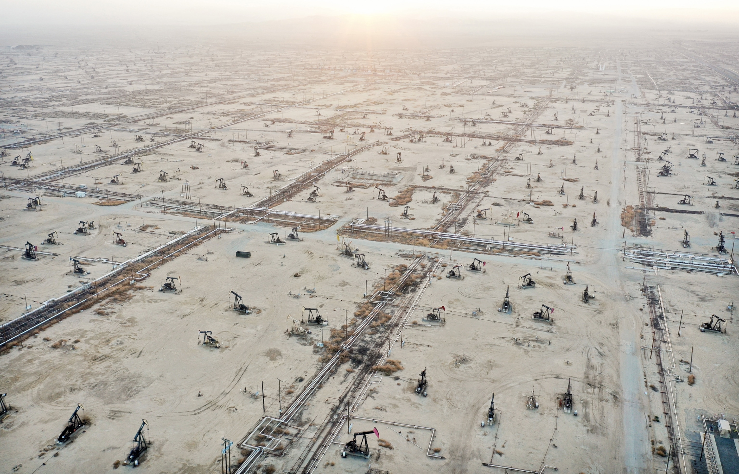 a desert environment with many pumpjacks at sunset