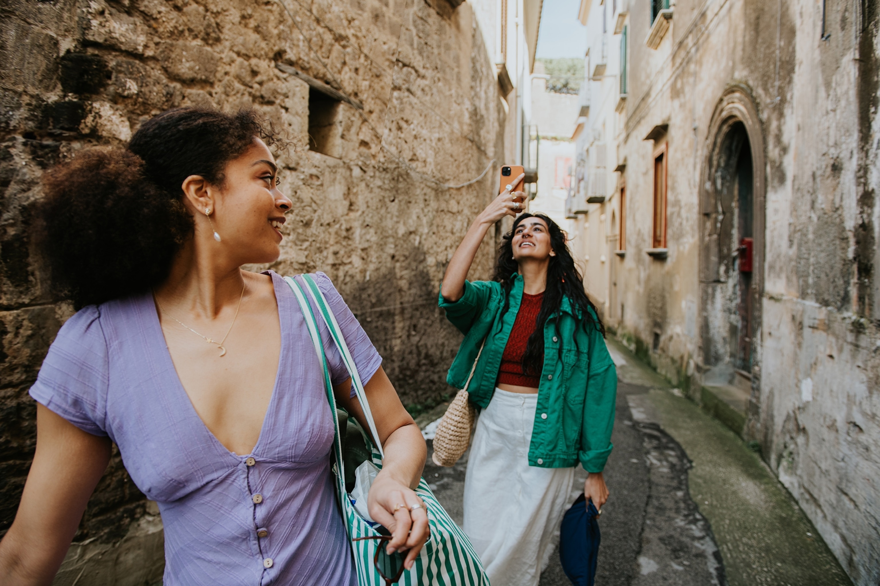 Two women walking and taking photos.