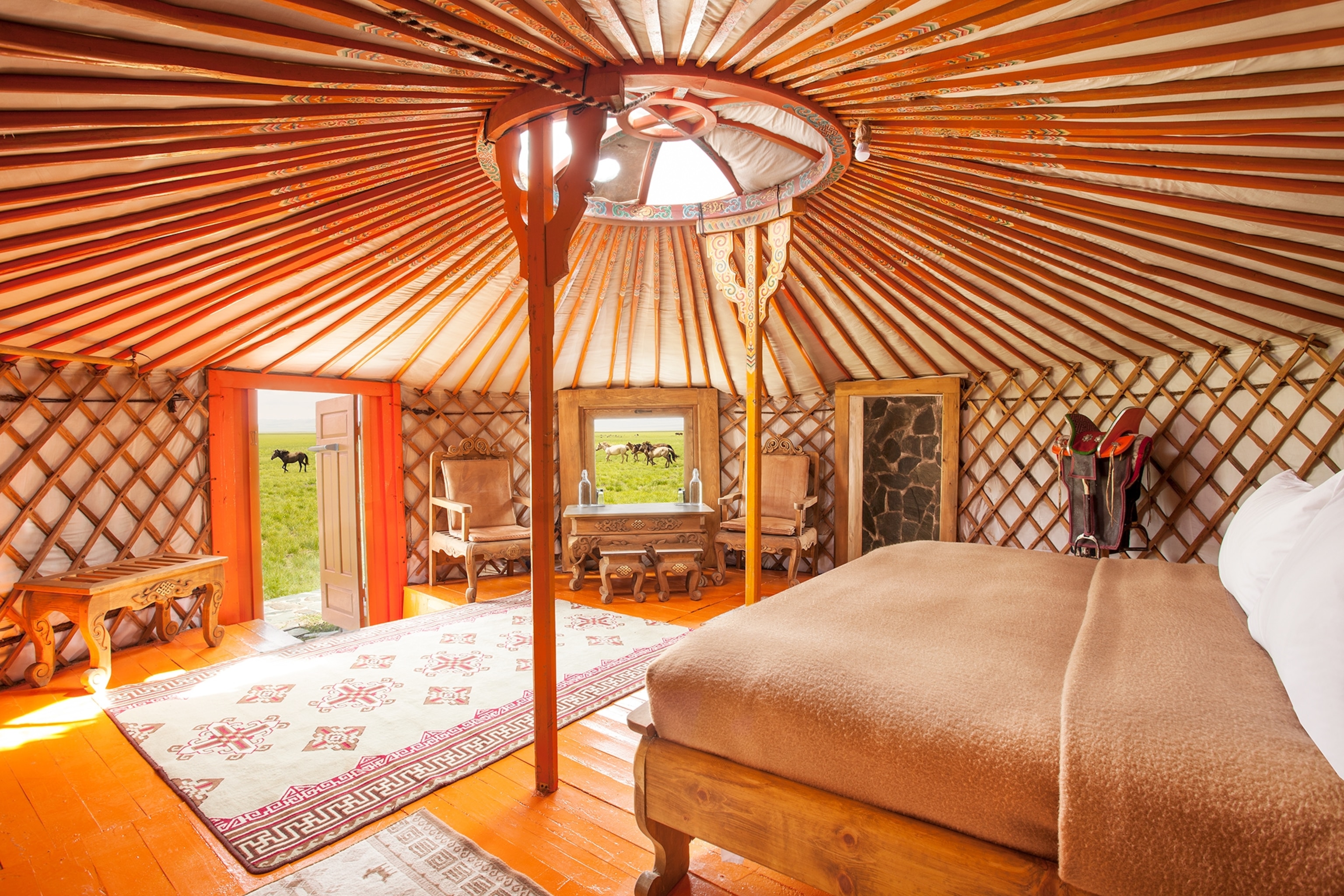 A room at the Three Camel Lodge looking towards a field where horses run past.