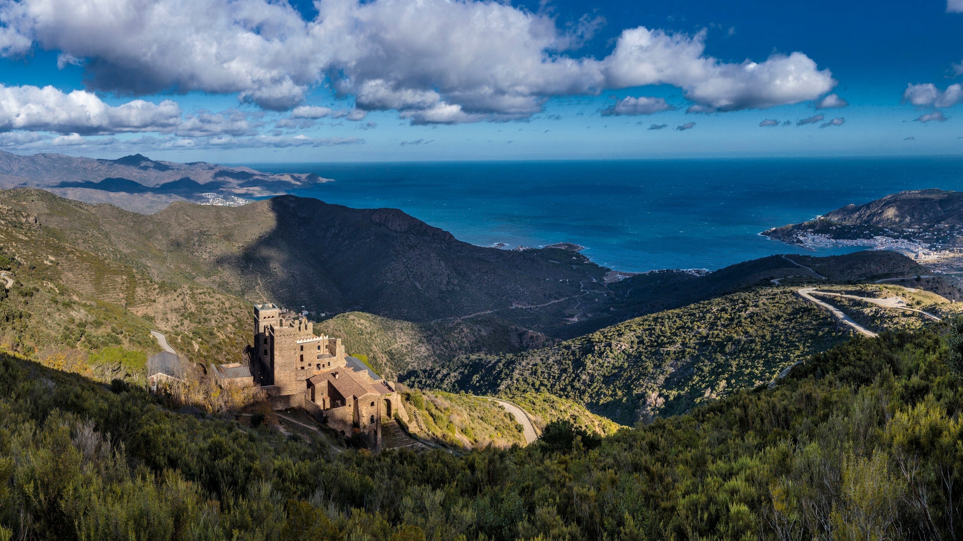 Sweeping views of the Pyrenees, out to the ocean. A castle can be seen on the left.