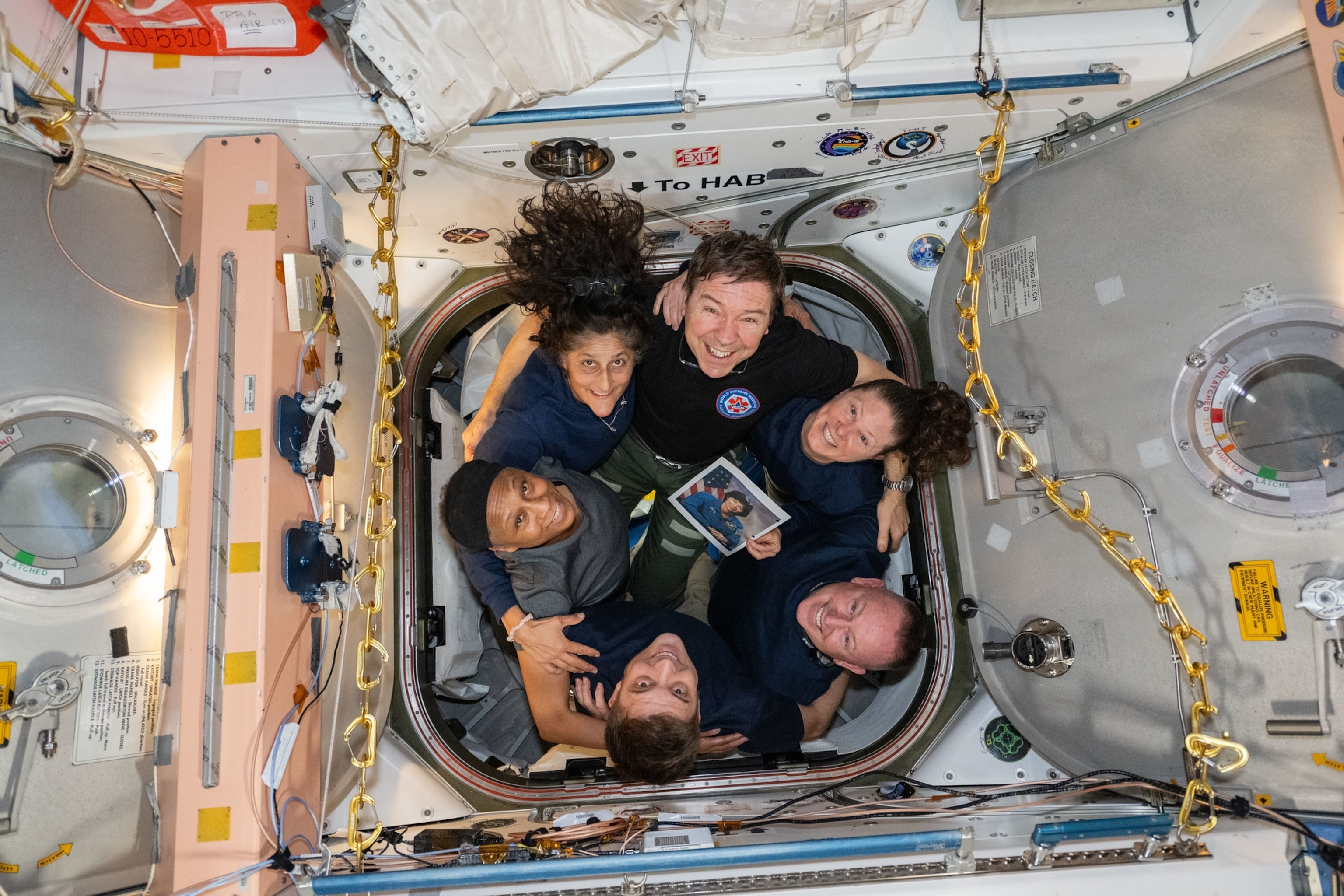 Group hug of six people in very narrow doorway.