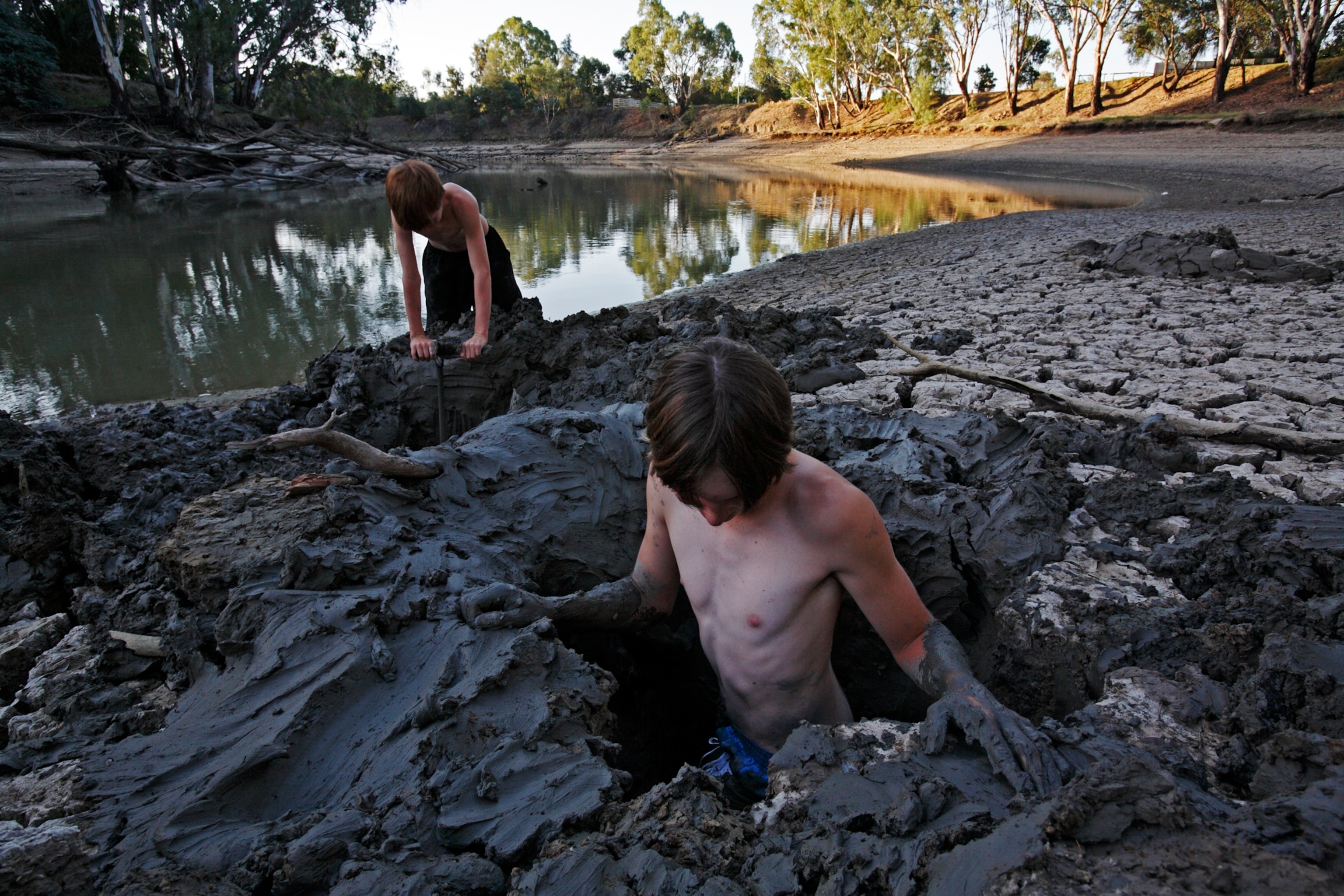 boys tunneling in the exposed, muddy bed of the Murrumbidgee River
