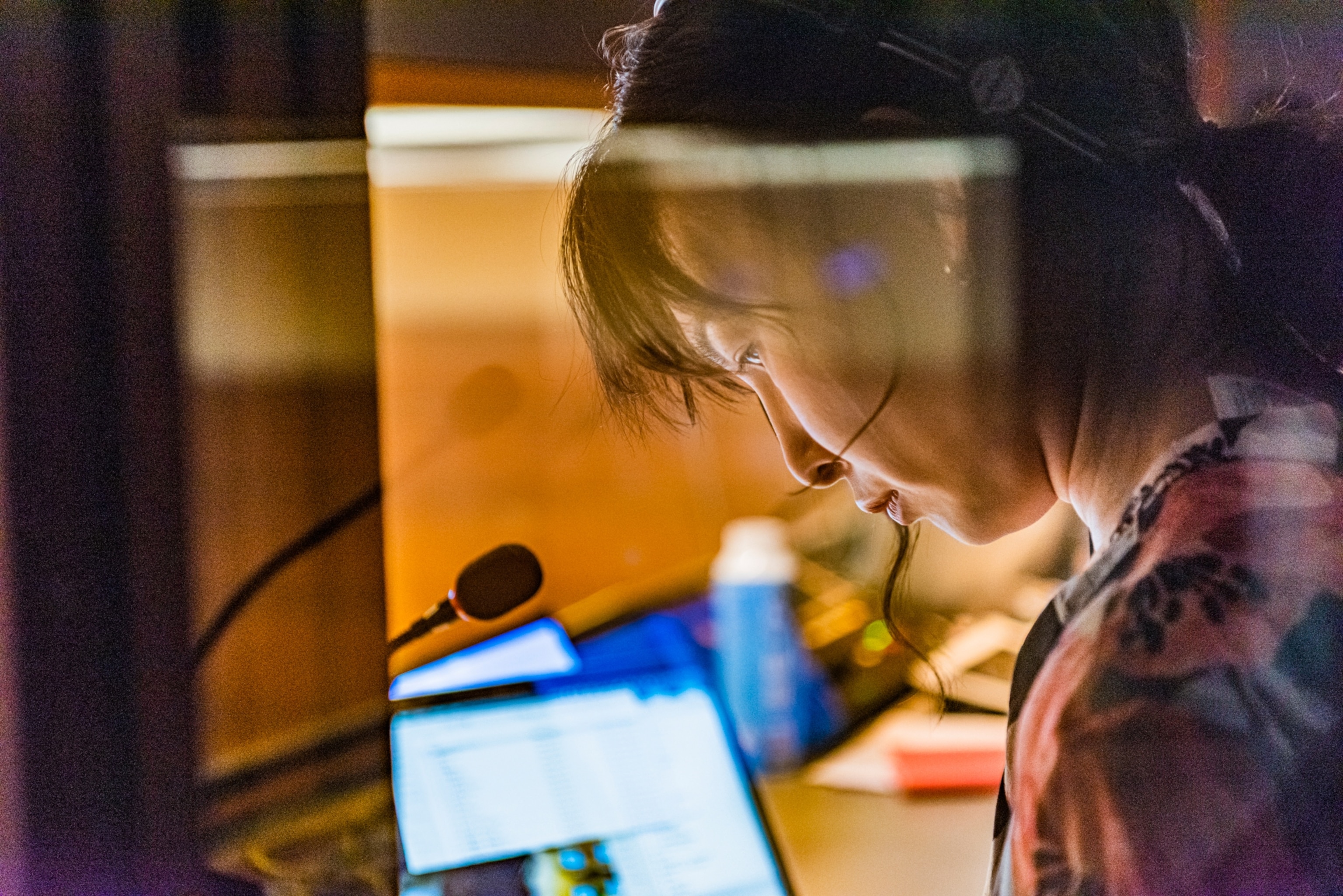 A close-up view of a Chinese woman wearing headphones and sitting by a microphone as she works as an interpreter.