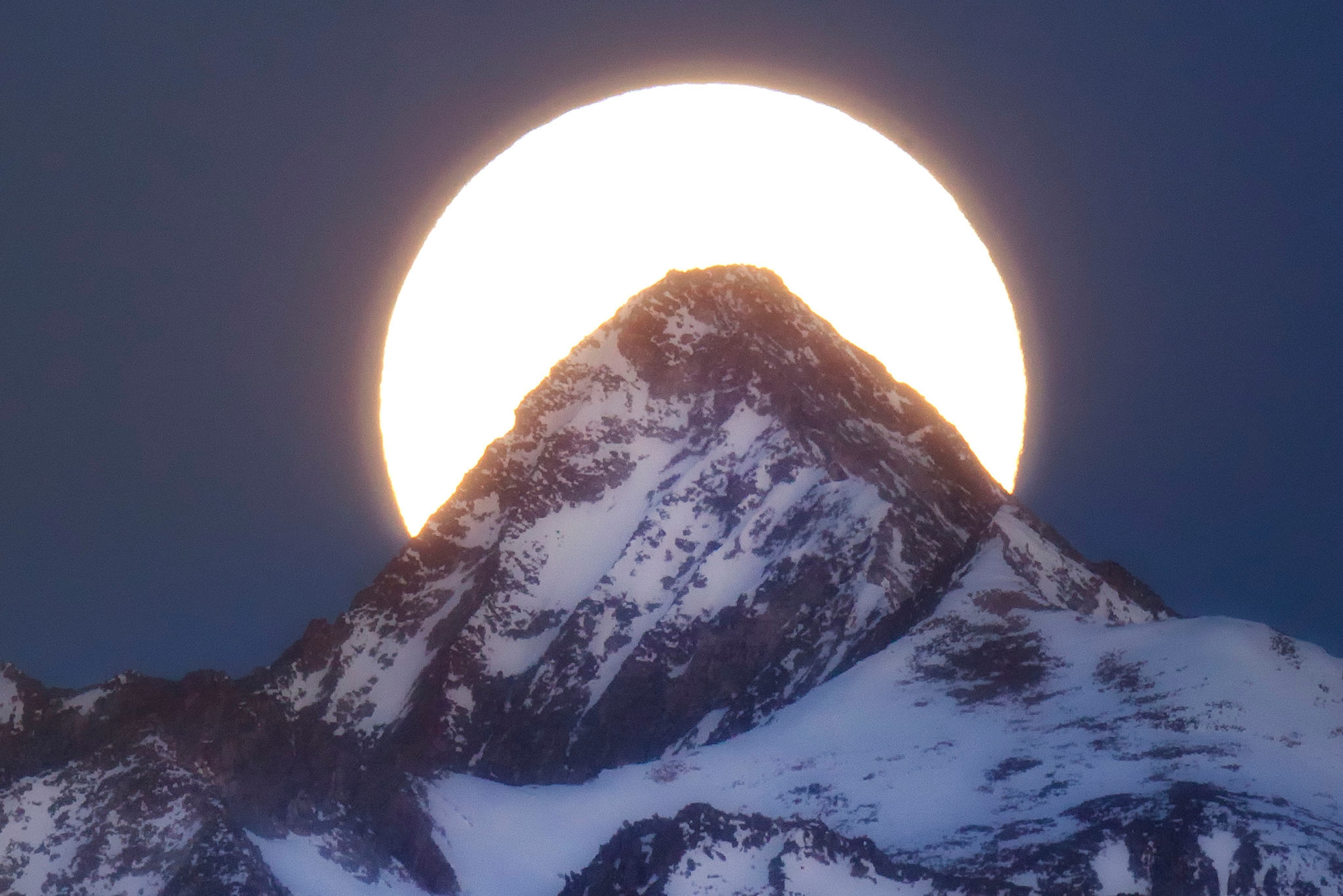 super moon behind a mountain peak