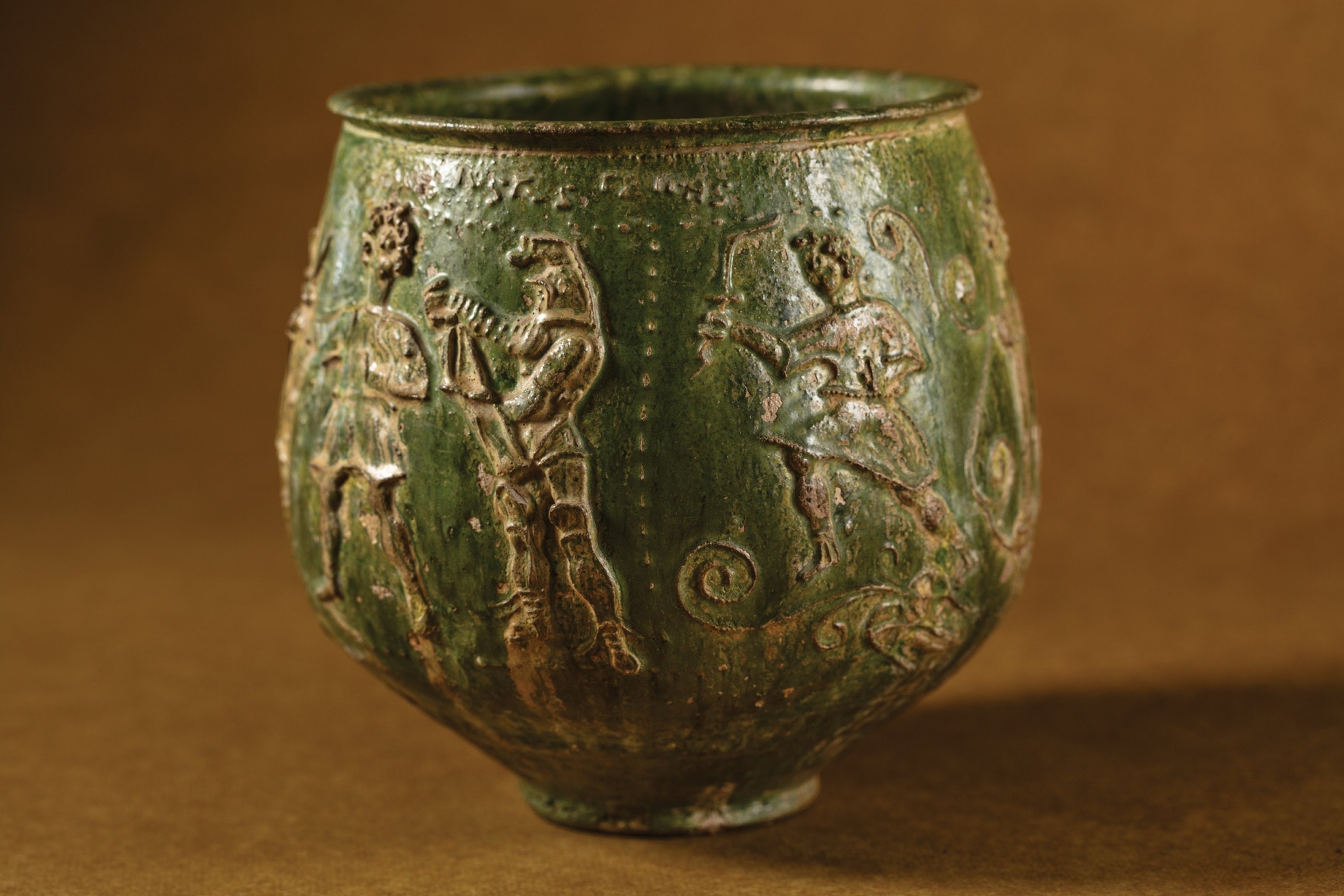 Picture of clay pot with raised ornament depicting gladiators.