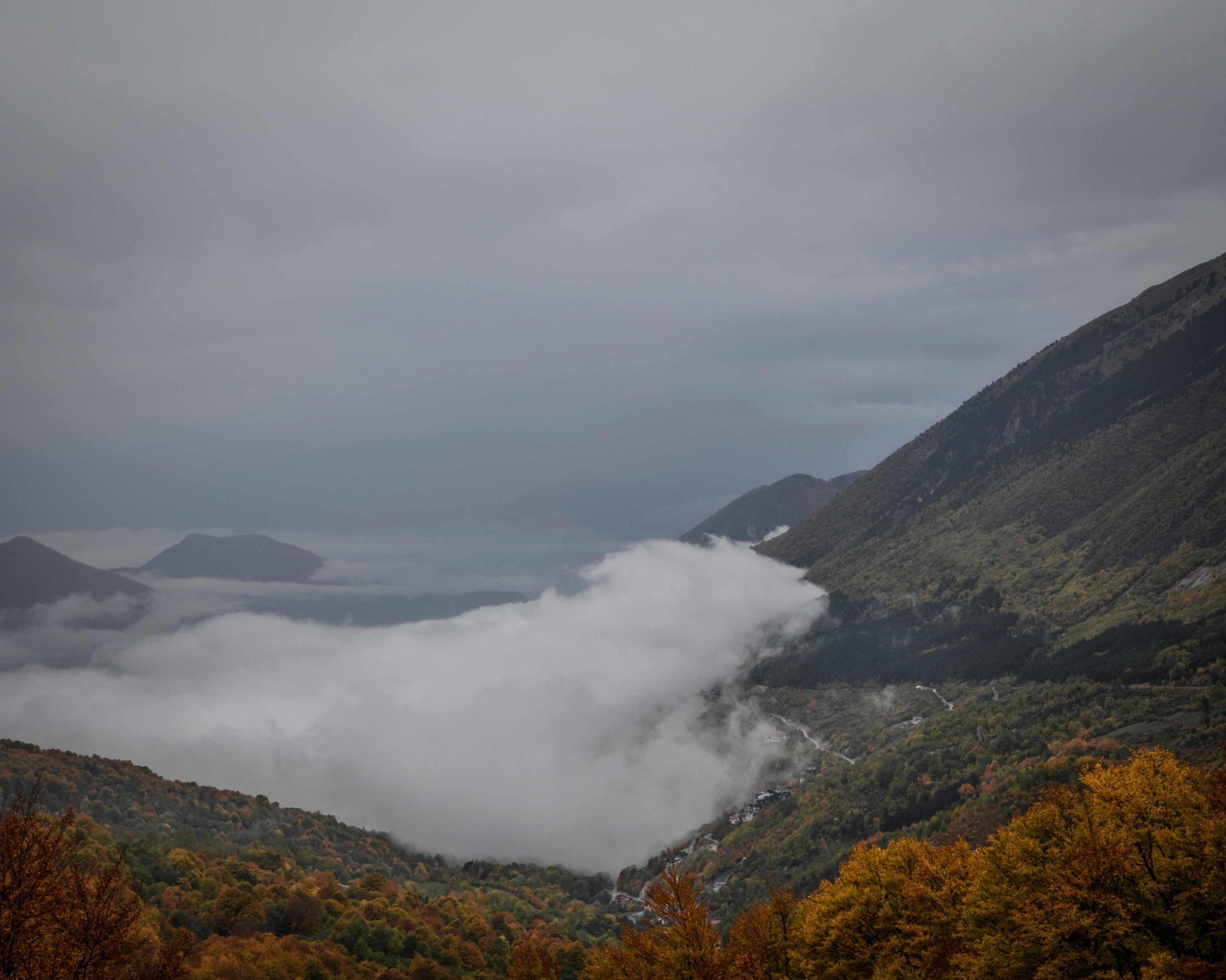 Picture of a mountainous valley with rolling fog at the bottom half.