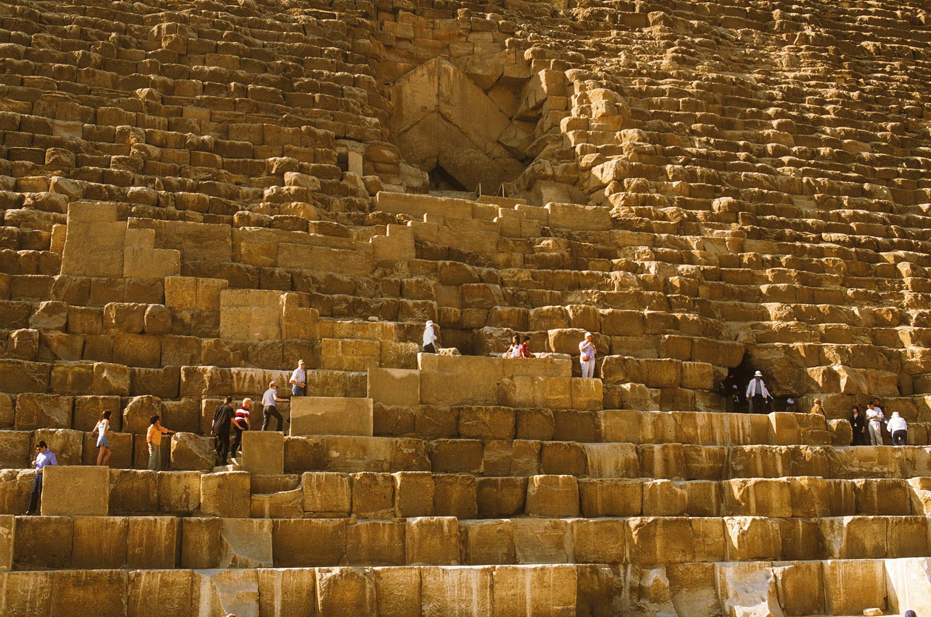 People climb and sit on the facade of Khufu's pyramid in Giza