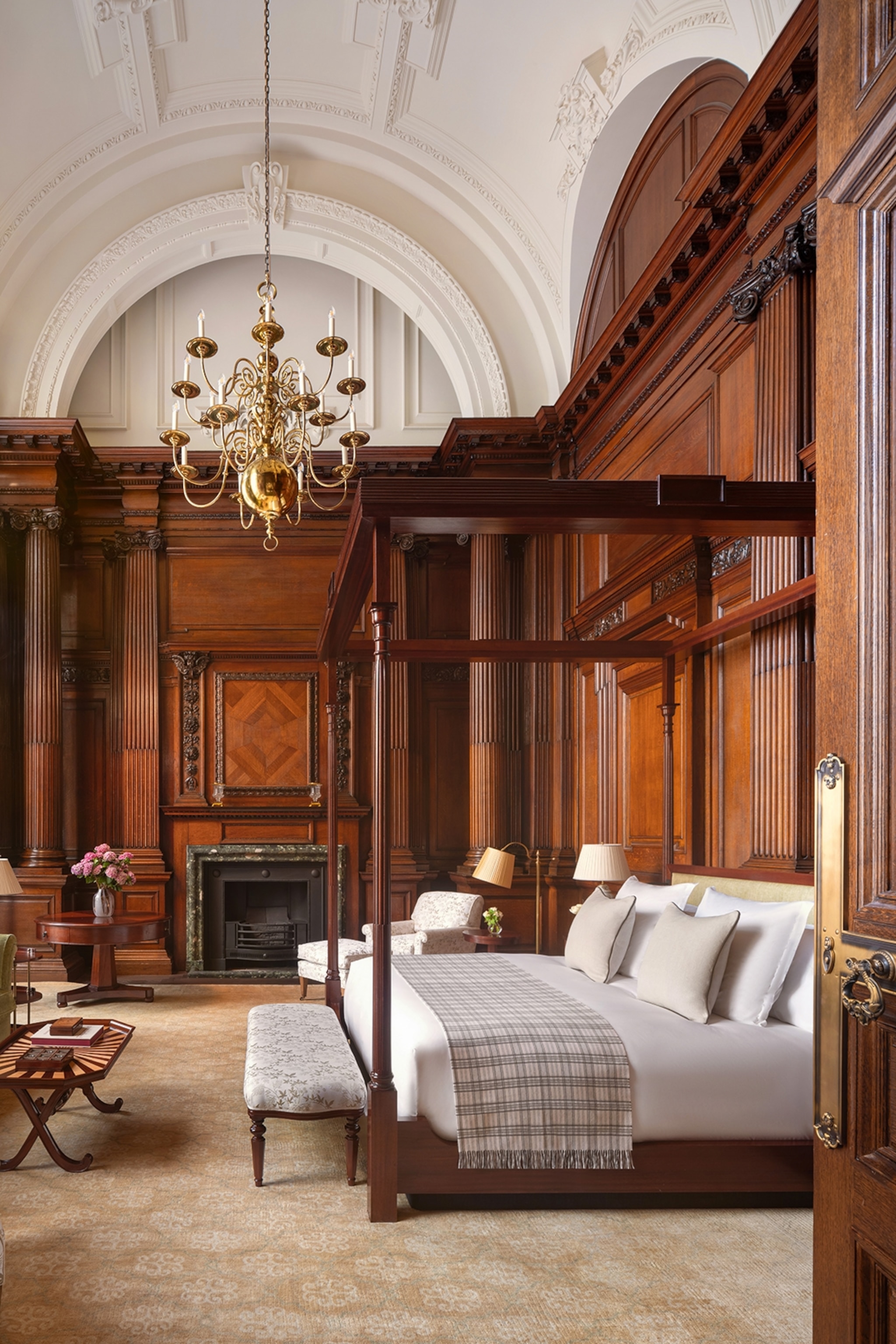 Grand four poster bed with wooden walls, high carved ceilings and a chandelier
