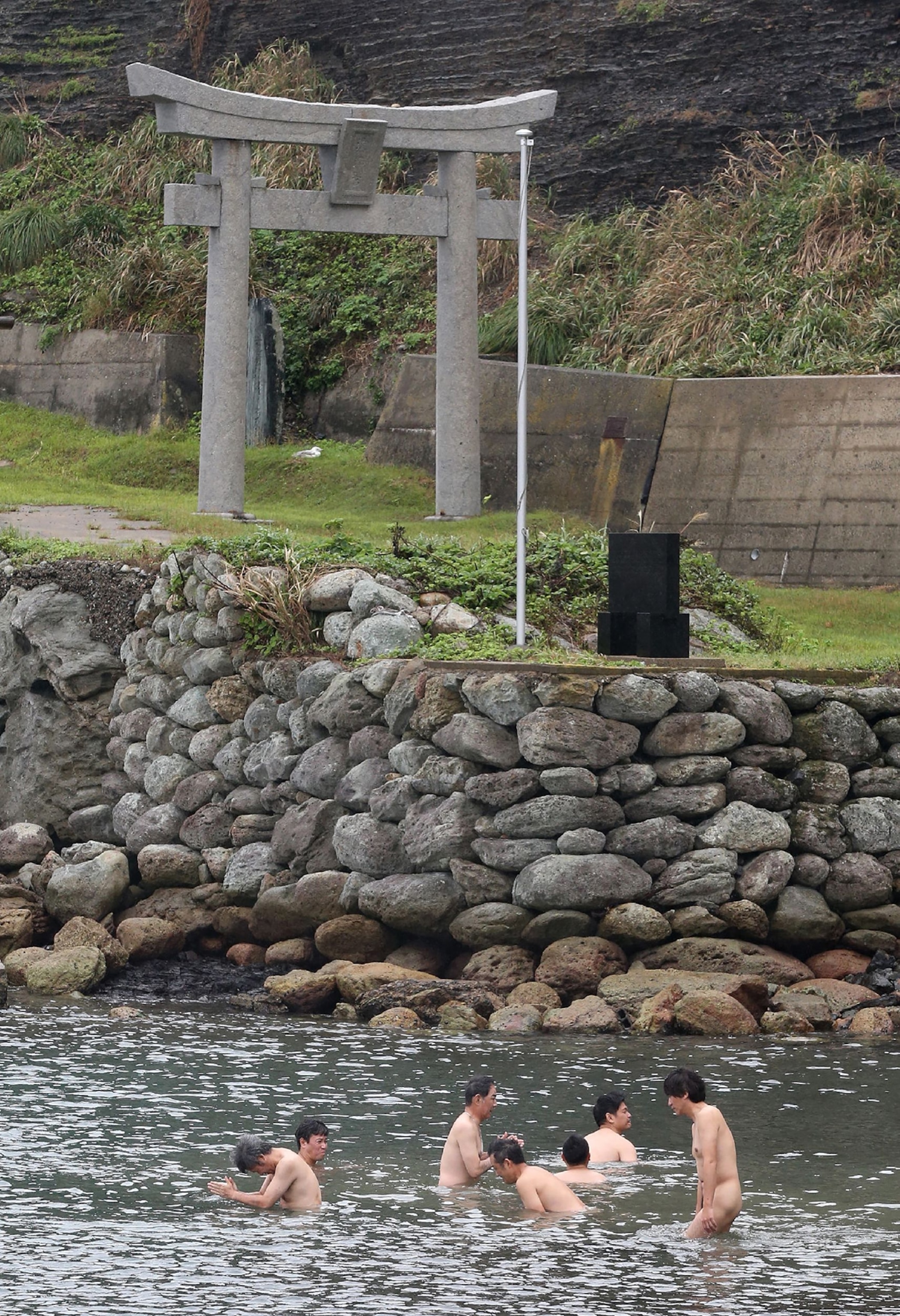 Naked men in water of of a coast built in stone.