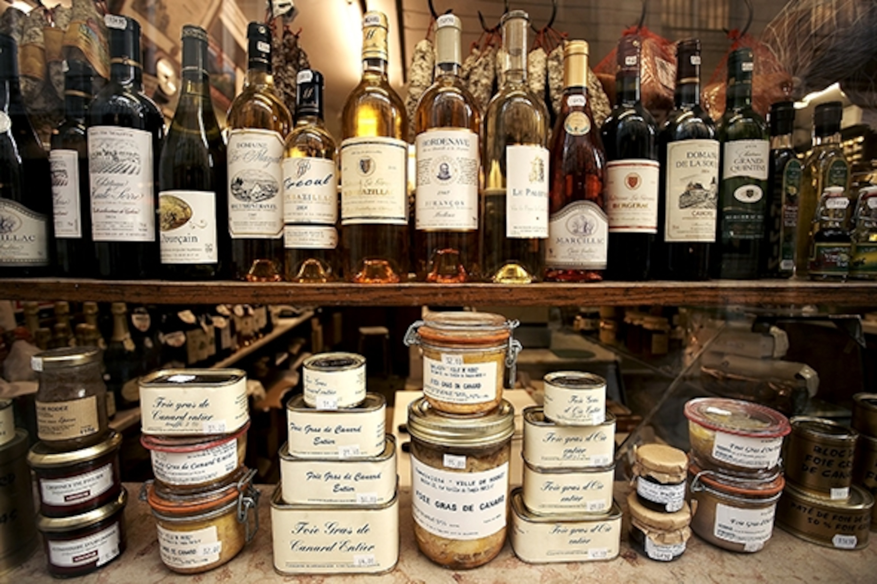 Jars of food and bottles of wine line the shelves of a French market