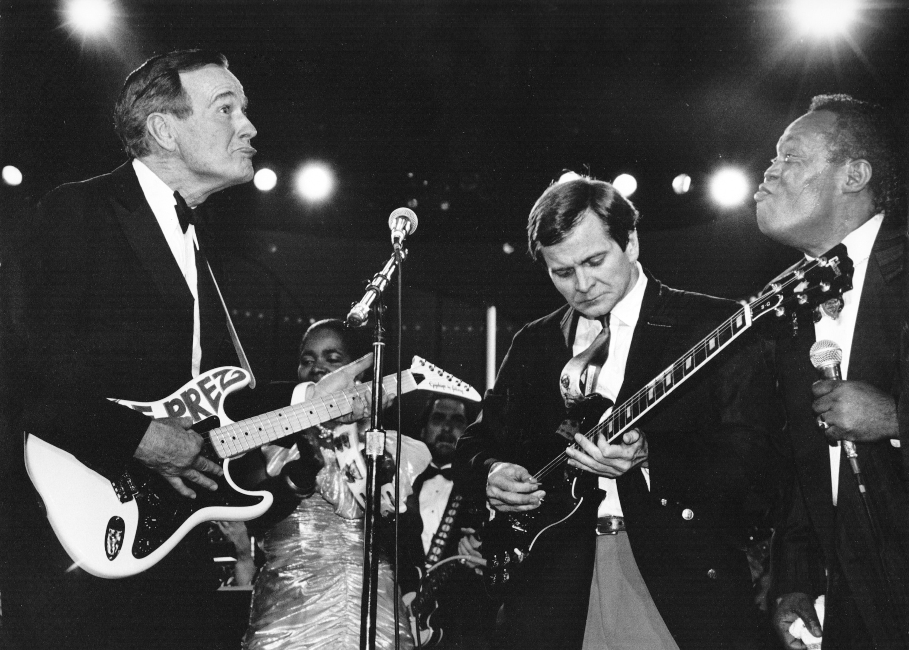 two people playing guitar while another has a microphone