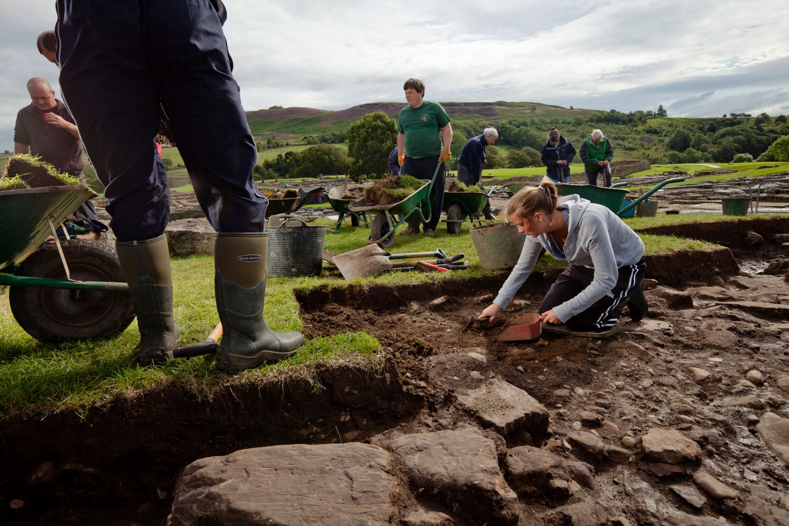 people in an archeology site carefully removing dirt