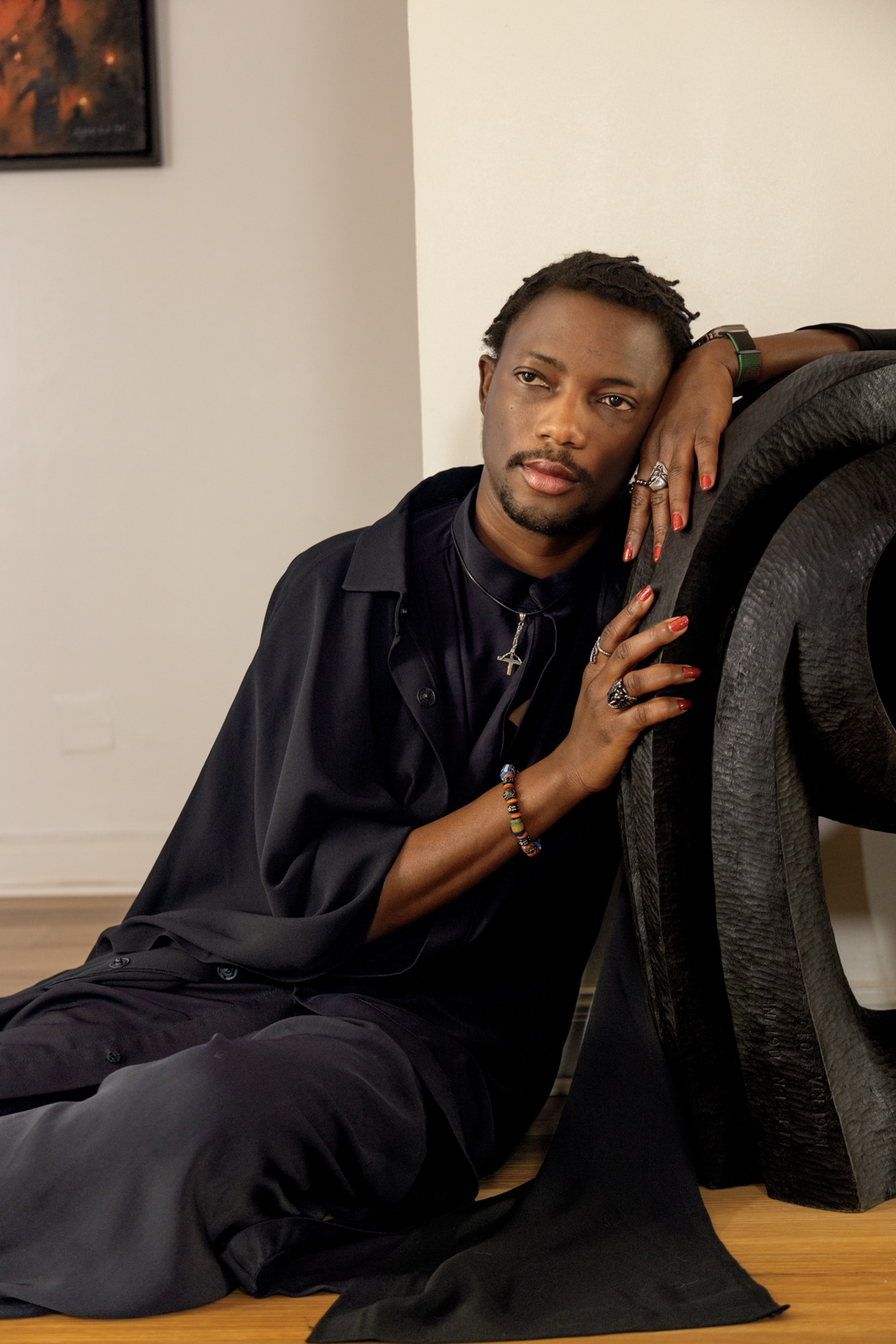 Portrait of Ezra sitting on the ground leaning against a grey felt structure