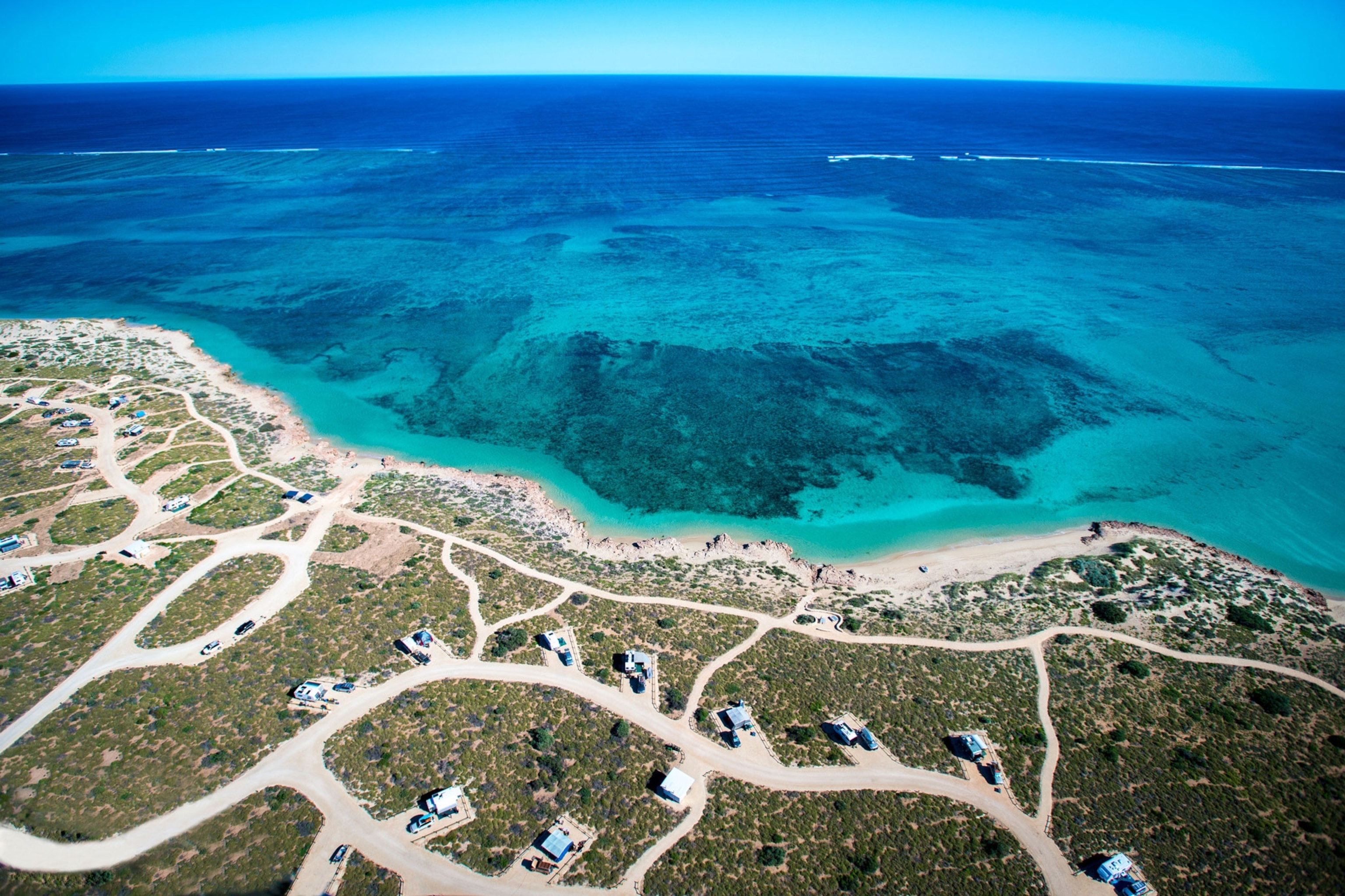 Aerial view of the blue-turquoise ocean and curving shoreline
