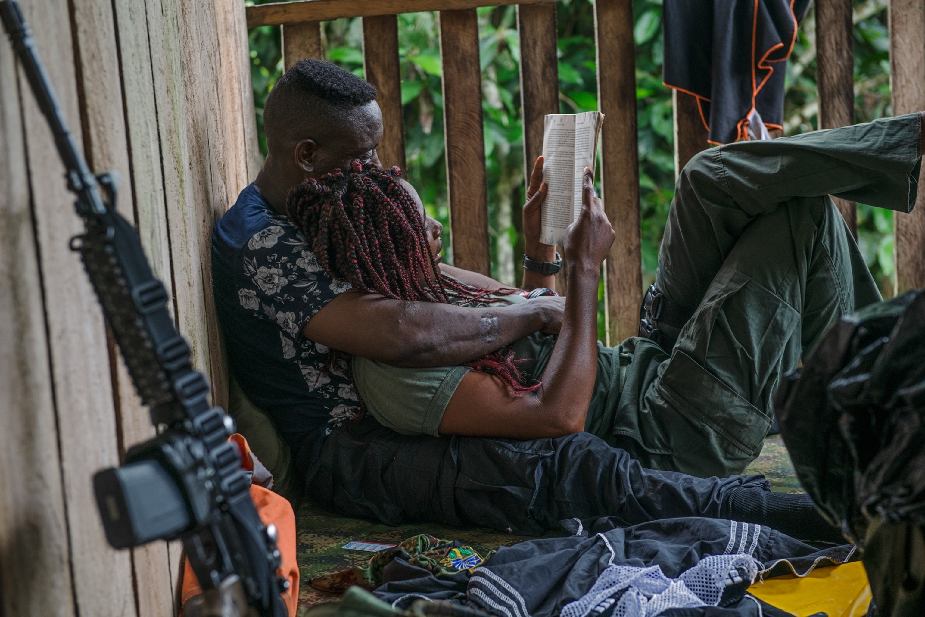 a woman lying on another person, reading a book