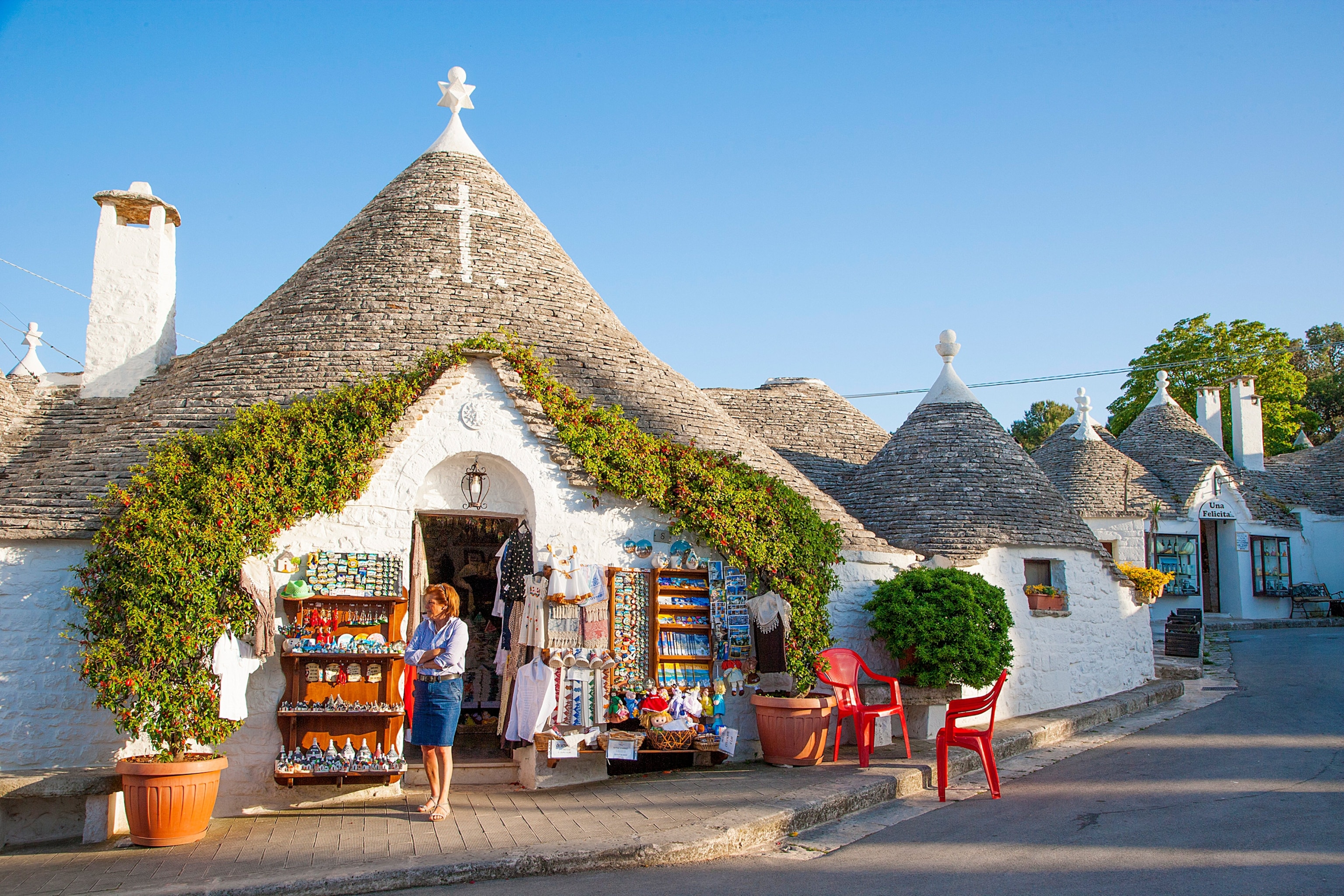 woman standing outside of a trulli in Alberobello, Italy