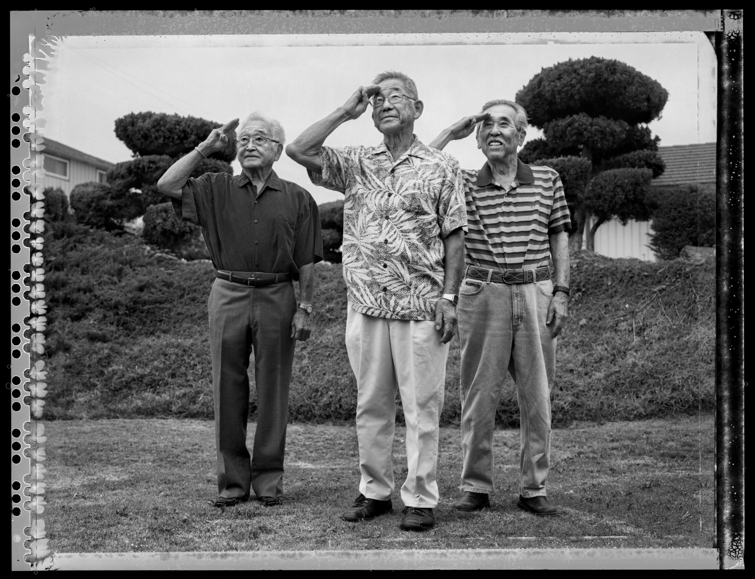 three elderly men standing outside saluting, shot on black and white