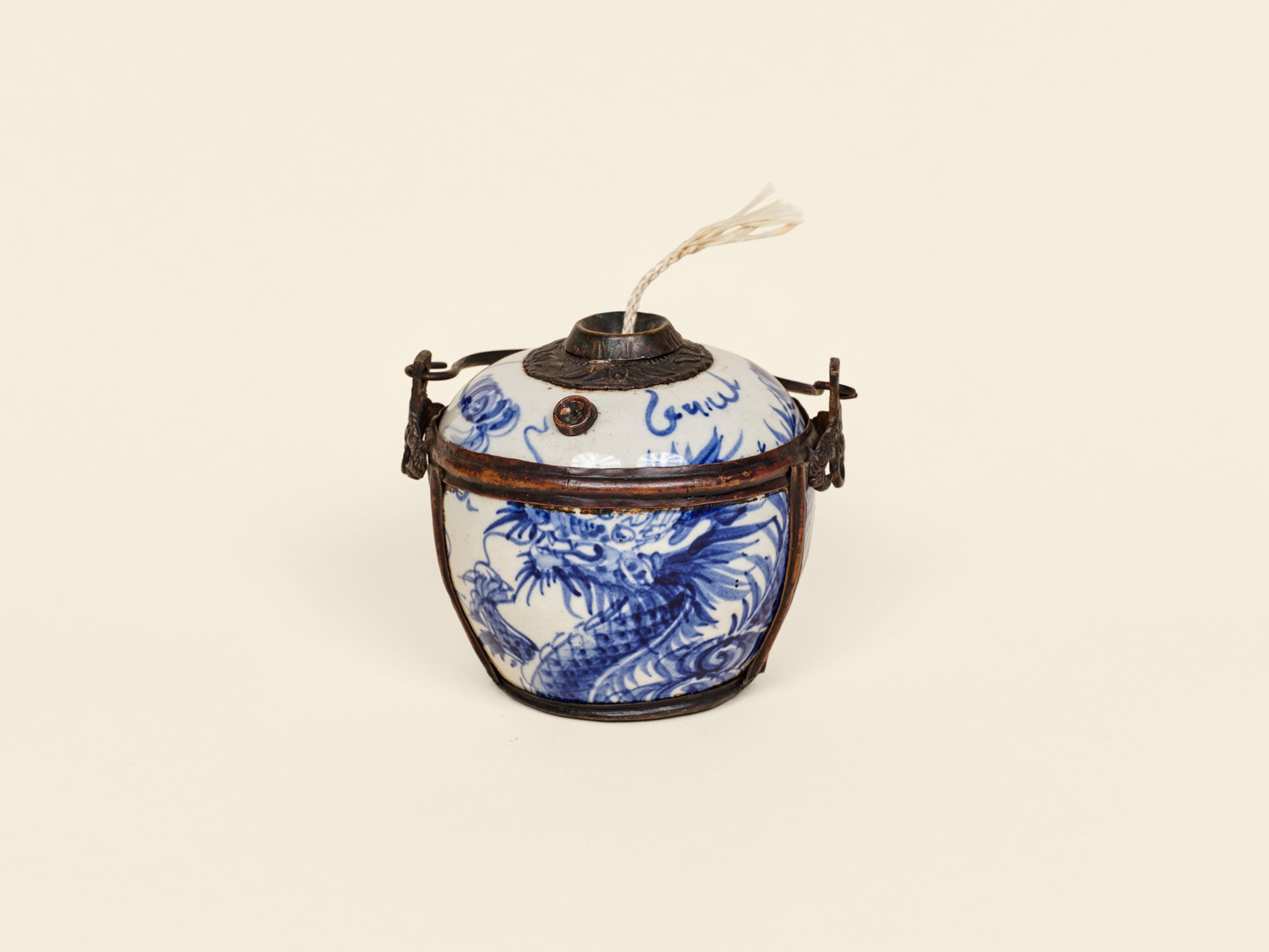 a porcelain oil lamp with a blue on white design depicting dragon's head, neck and a claw replacement wick (not original), surrounded by metal "cage".