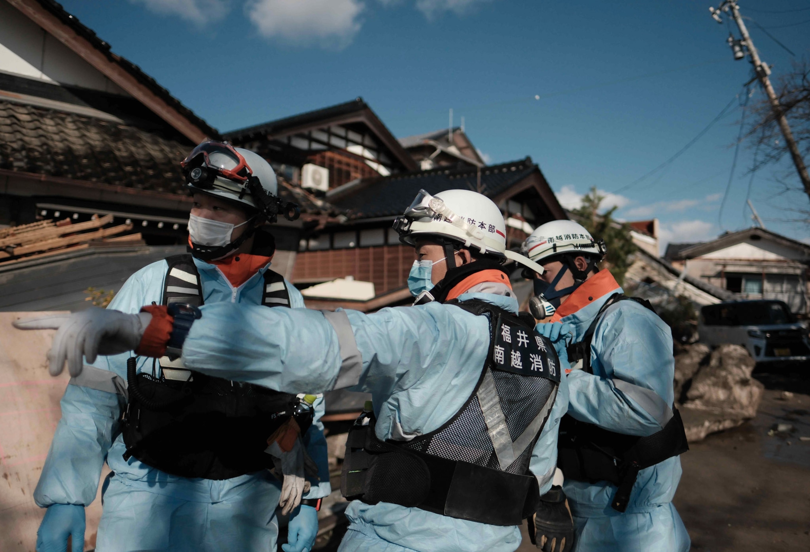 Fire fights in soft blue are center frame as they search after an earthquake.