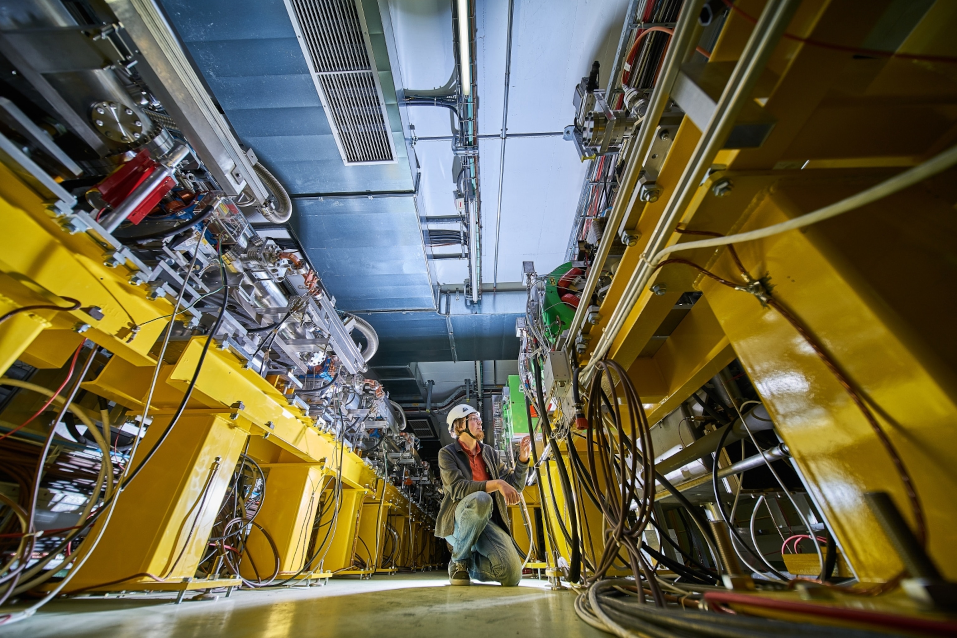 a man stands in an aisle of metal wiring and piping