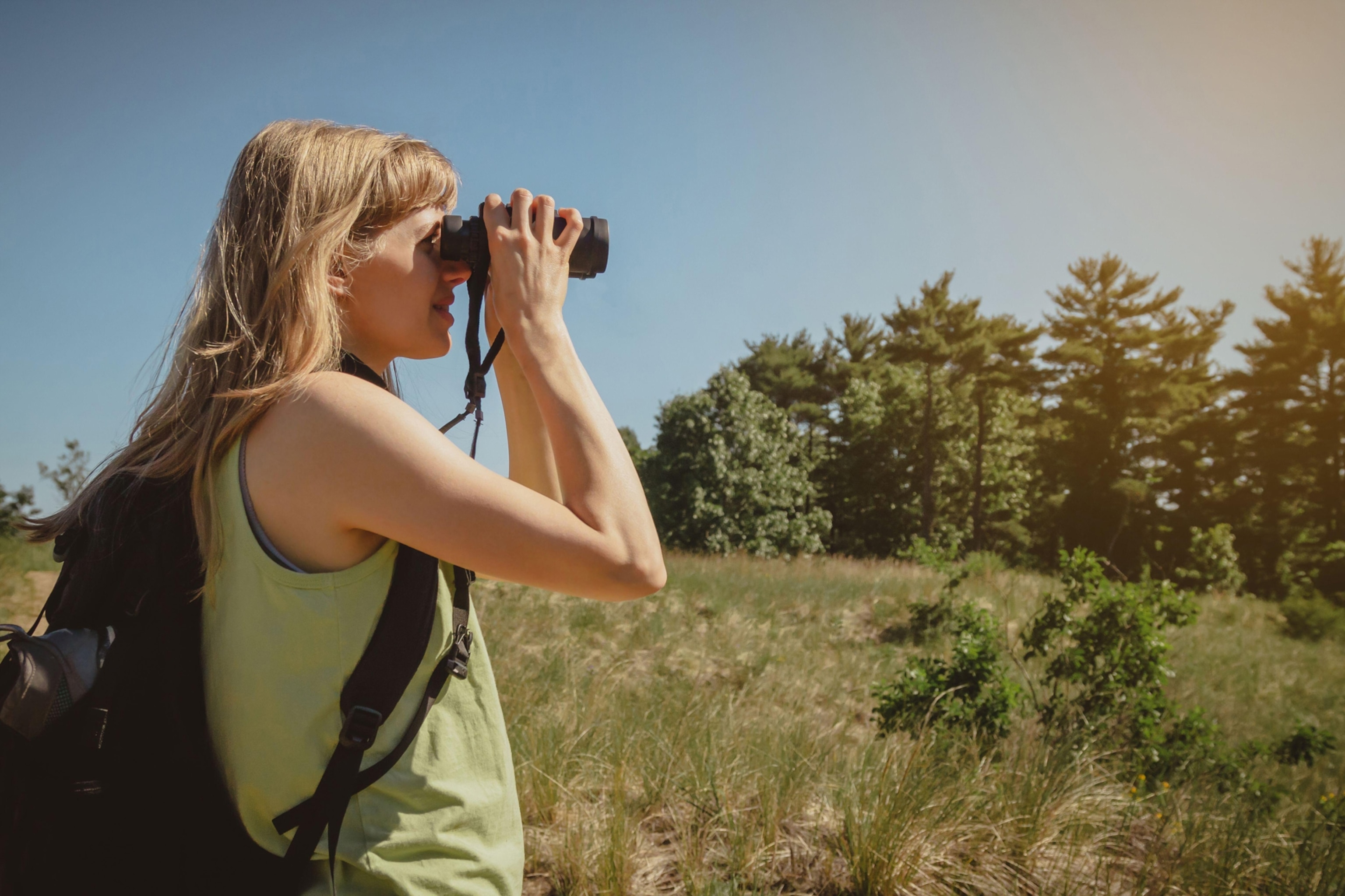 Young woman bird watching with binoculars at Indiana Dunes State Park.