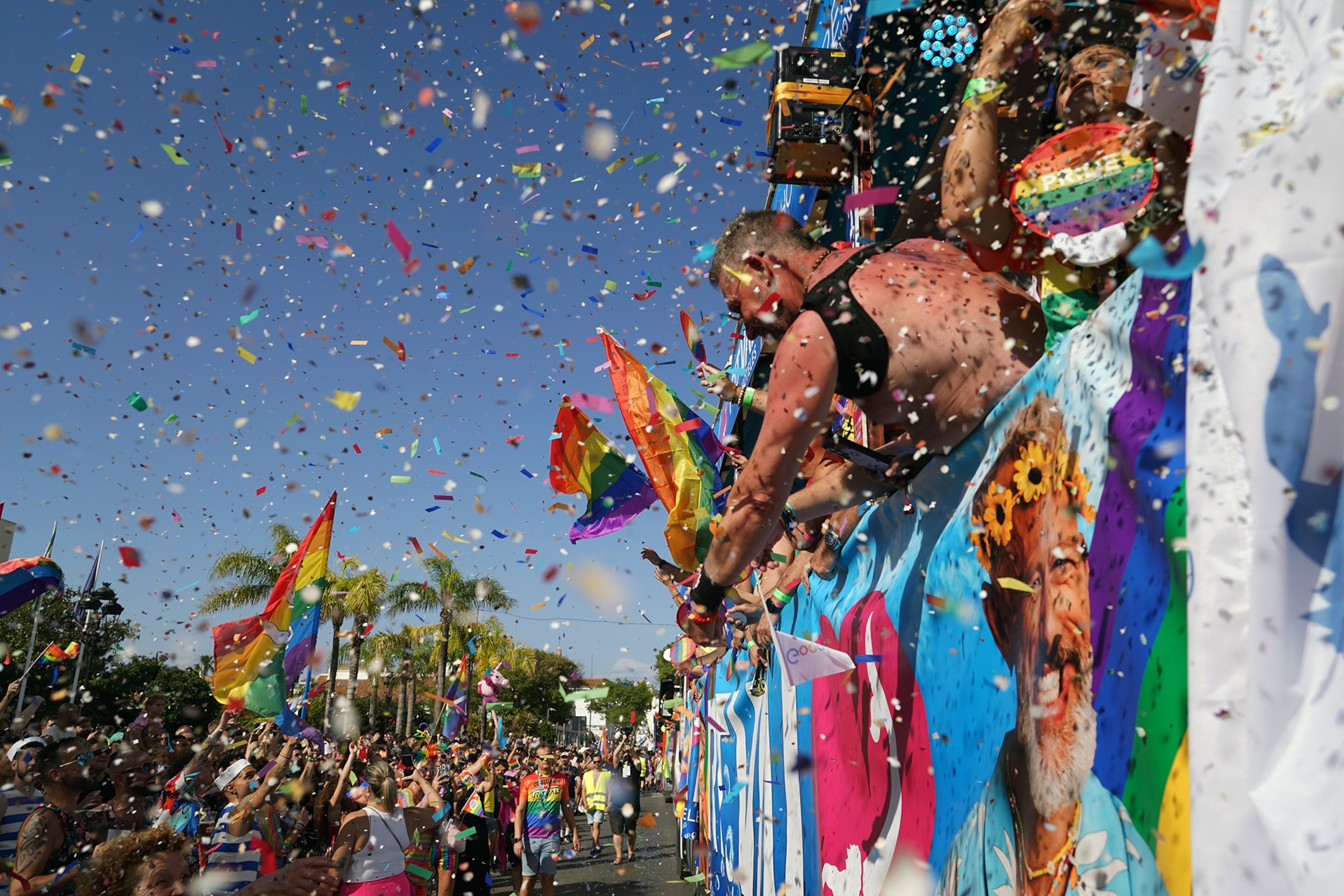 Confetti falls from the sky as people wave flags.