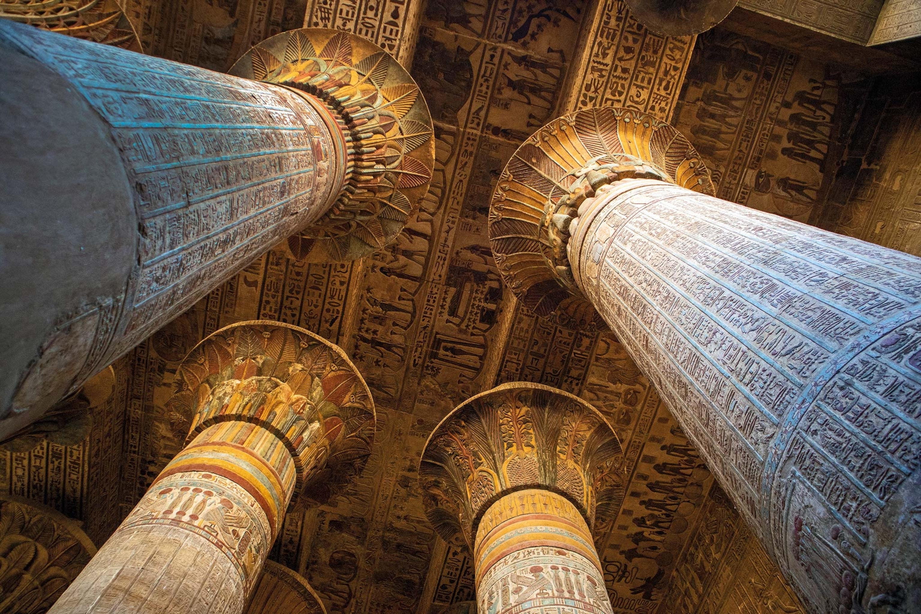 A view of the ceiling and its paintings in a temple from the ground, with carved columns