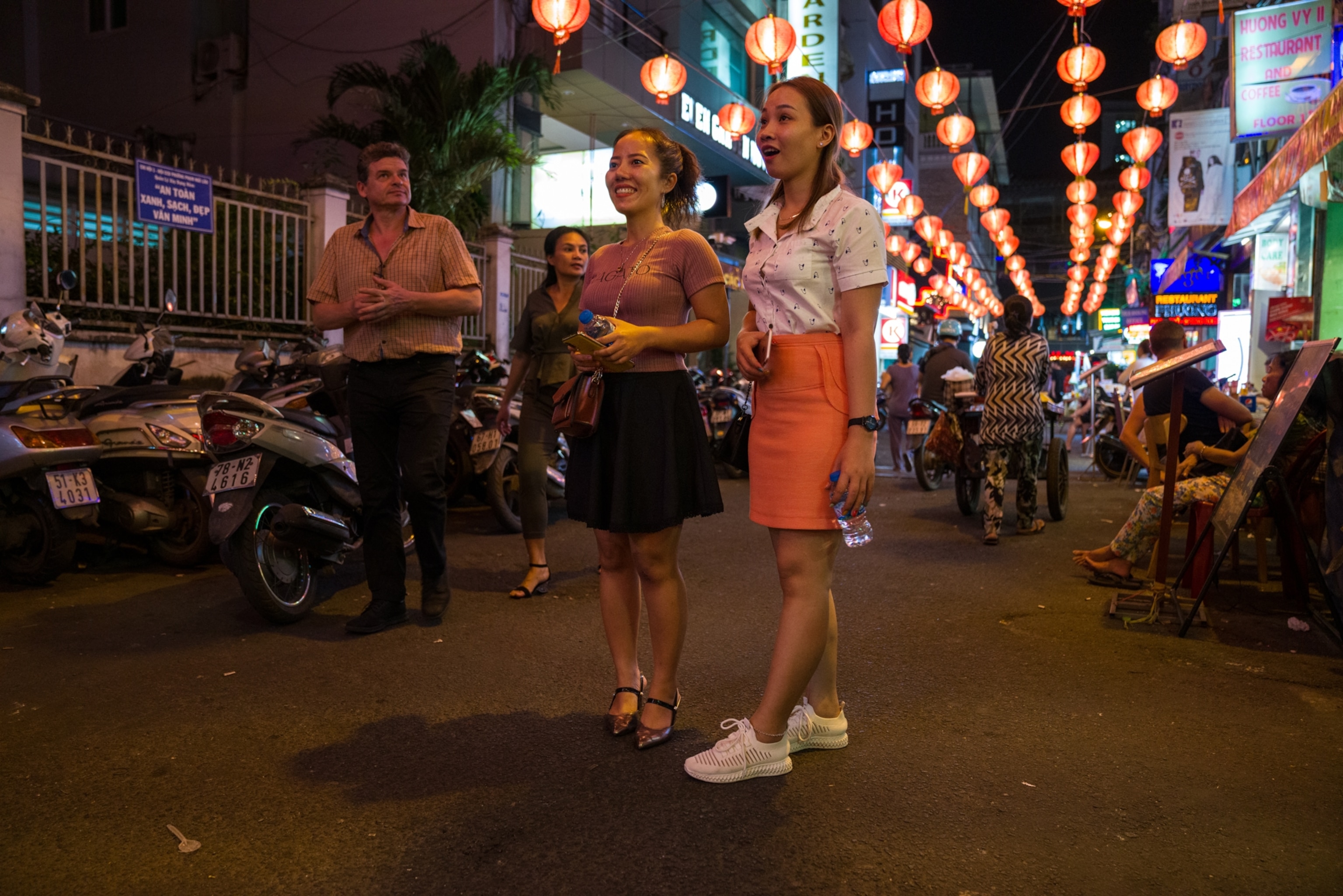 women walking down a street lit by lanterns at night